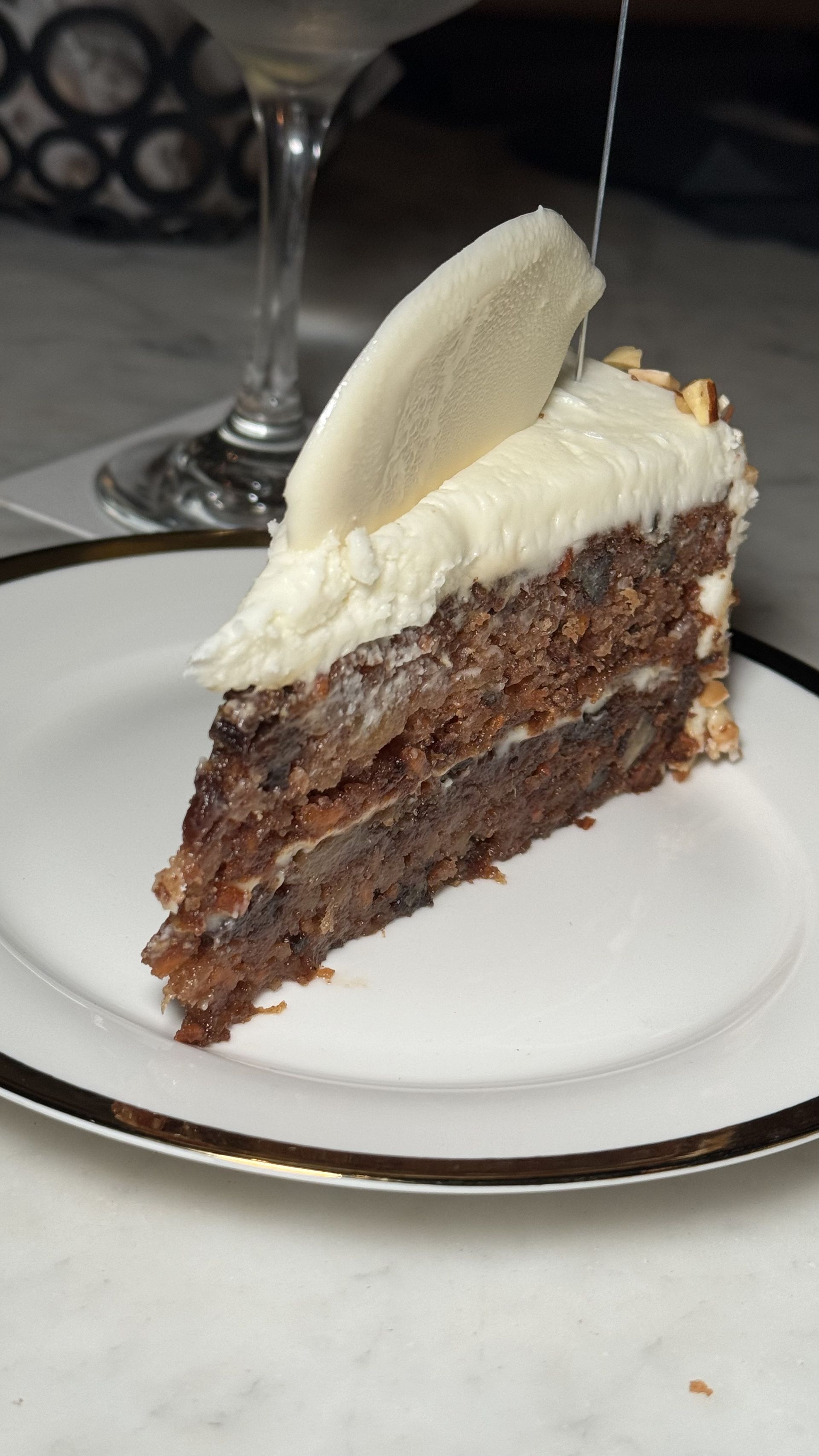 The Beverly - A slice of chocolate cake with white frosting on a white plate