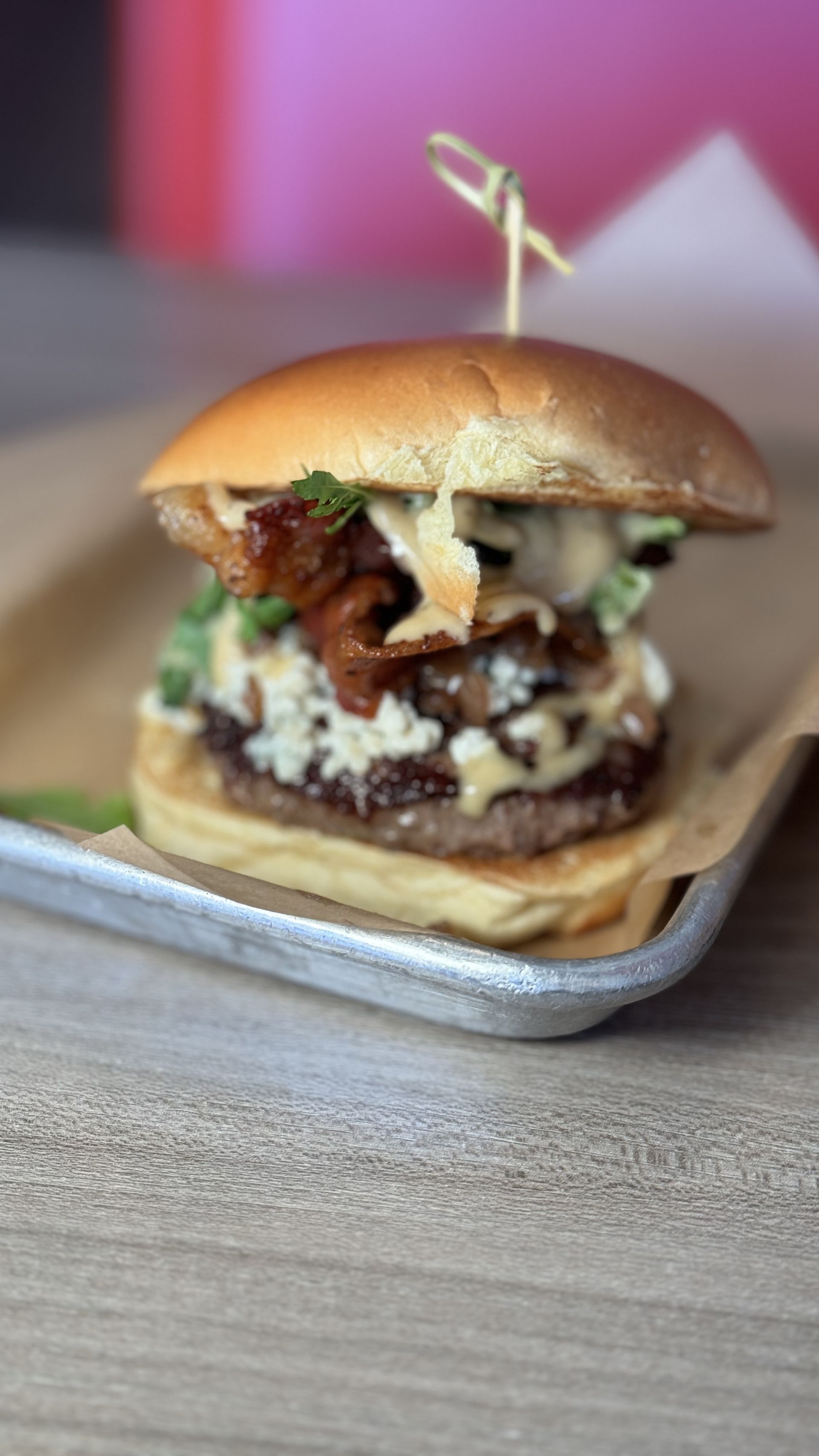 Aioli Gourmet Burgers - A close up of a hamburger on a tray on a table.