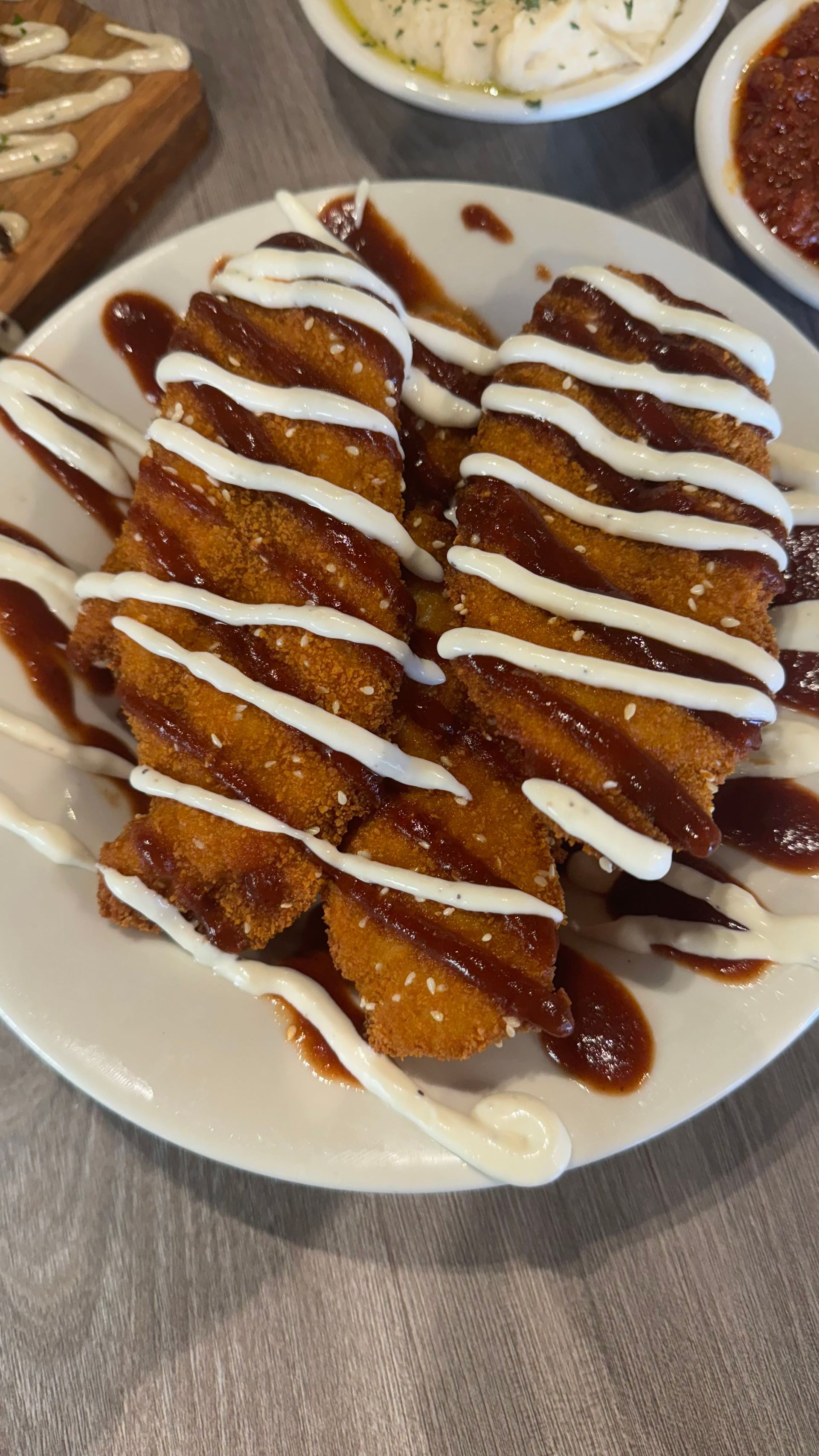 Fata Morgana - A white plate topped with fried food and sauce on a table.
