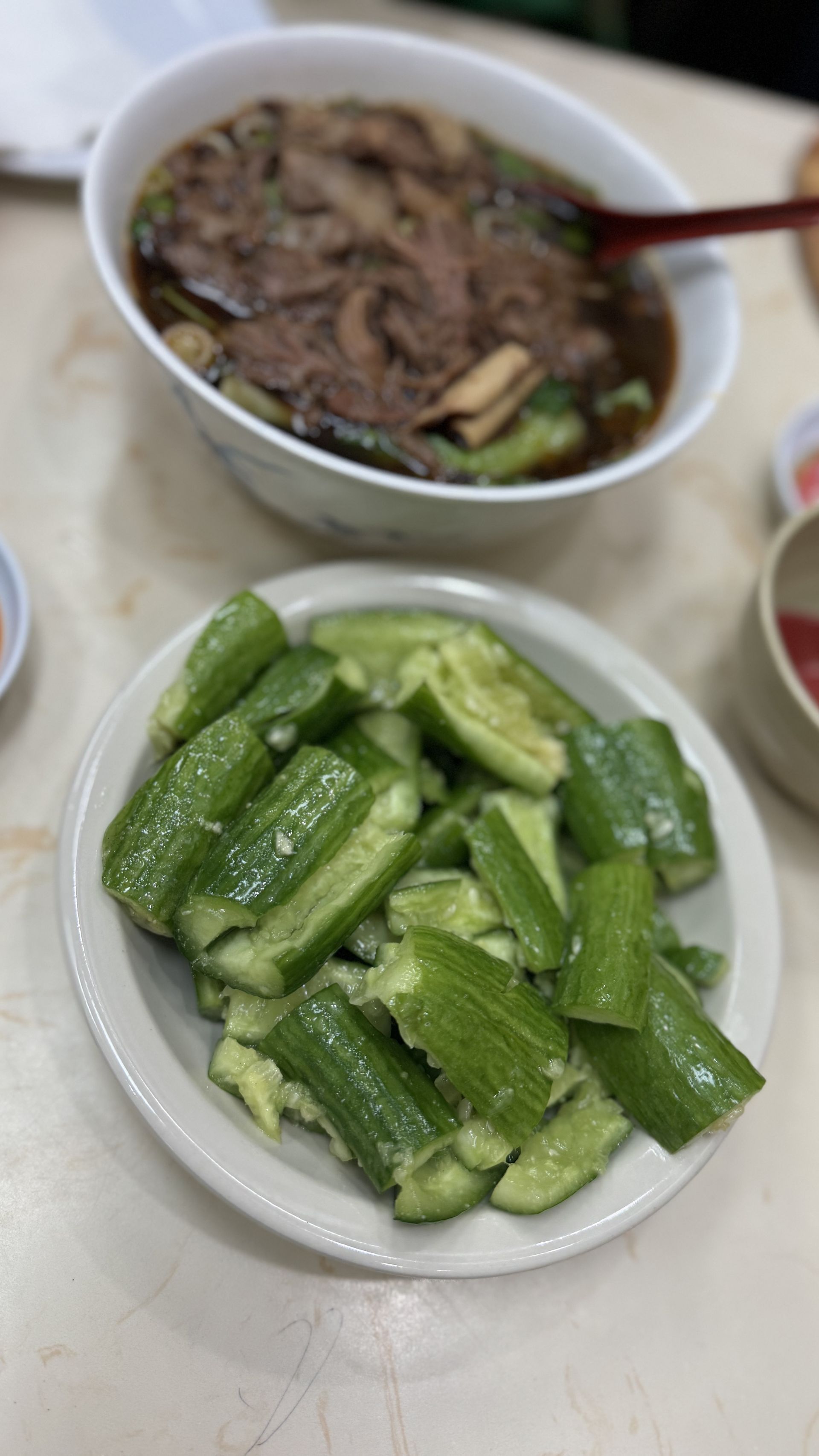 Happy Baos - There is a bowl of soup and a plate of vegetables on the table.