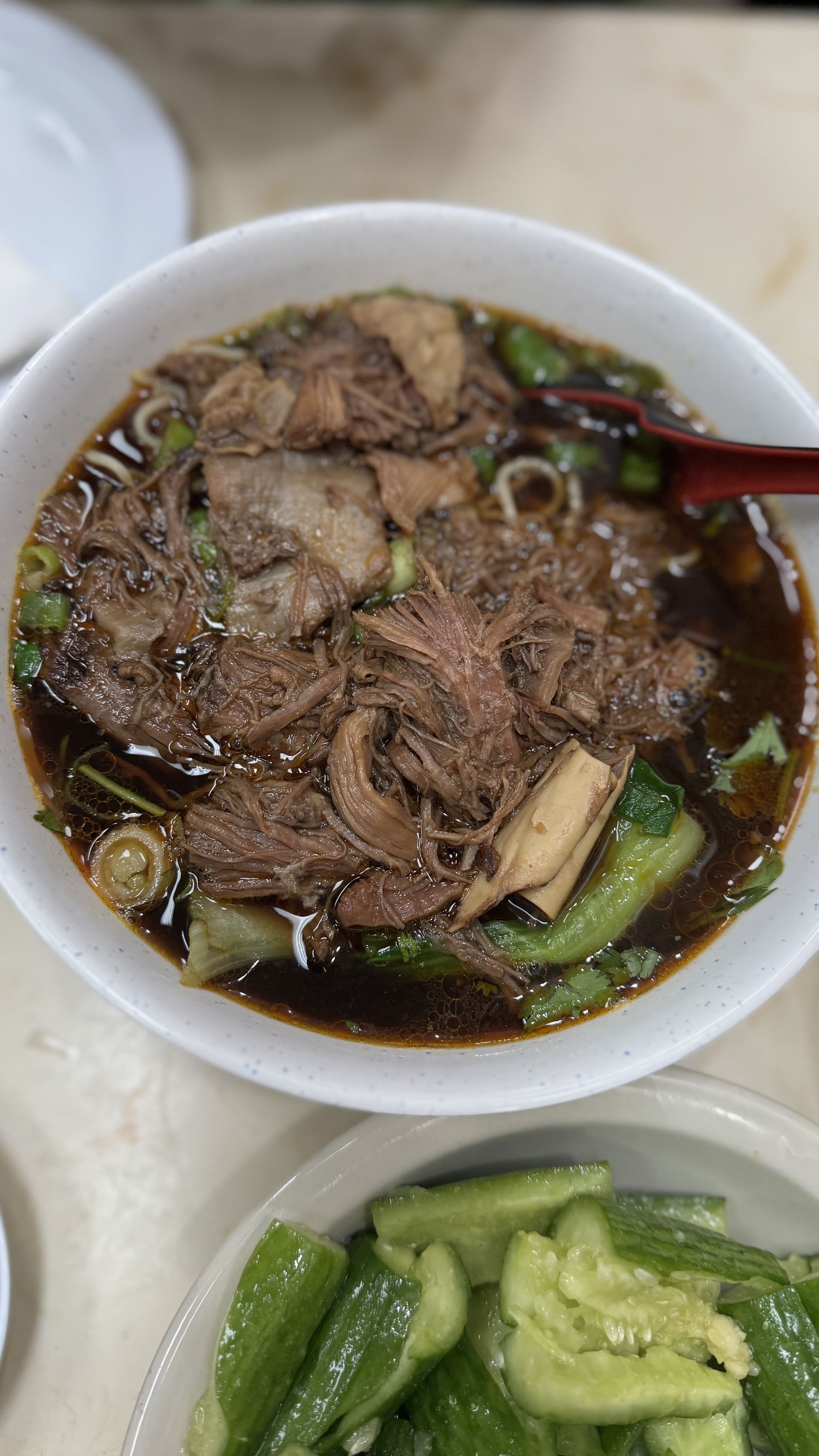 Happy Baos - A bowl of soup with meat and vegetables on a table.