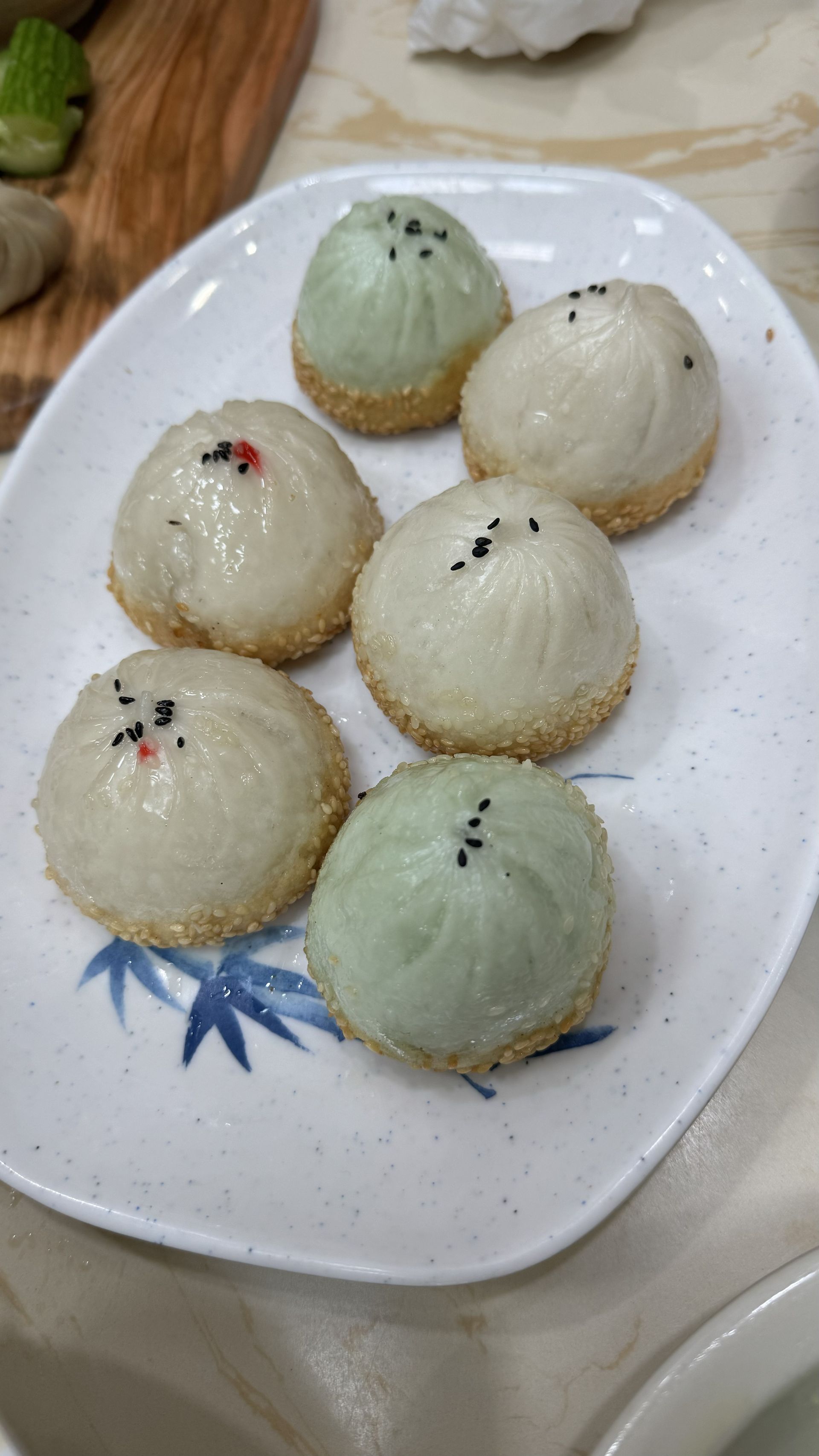 Happy Baos - A white plate topped with a bunch of dumplings on a table.