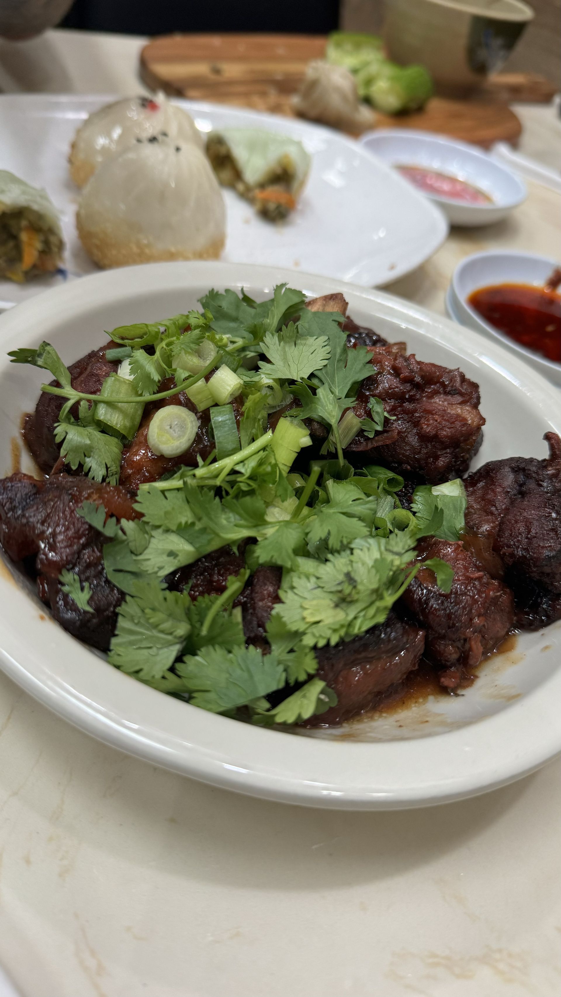 Happy Baos - A white plate topped with meat and vegetables on a table.