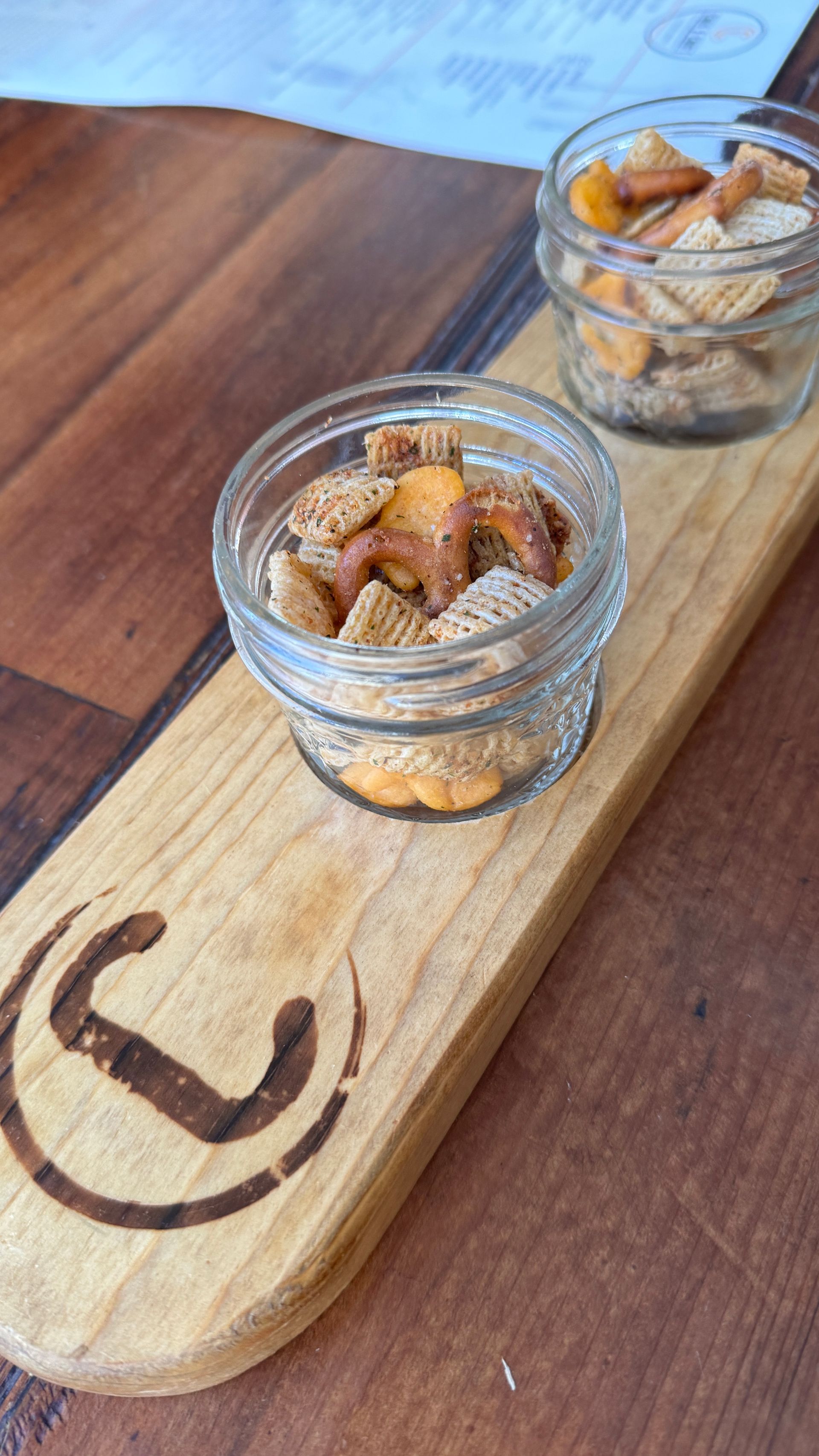 A wooden tray with three bowls of snacks on it.
