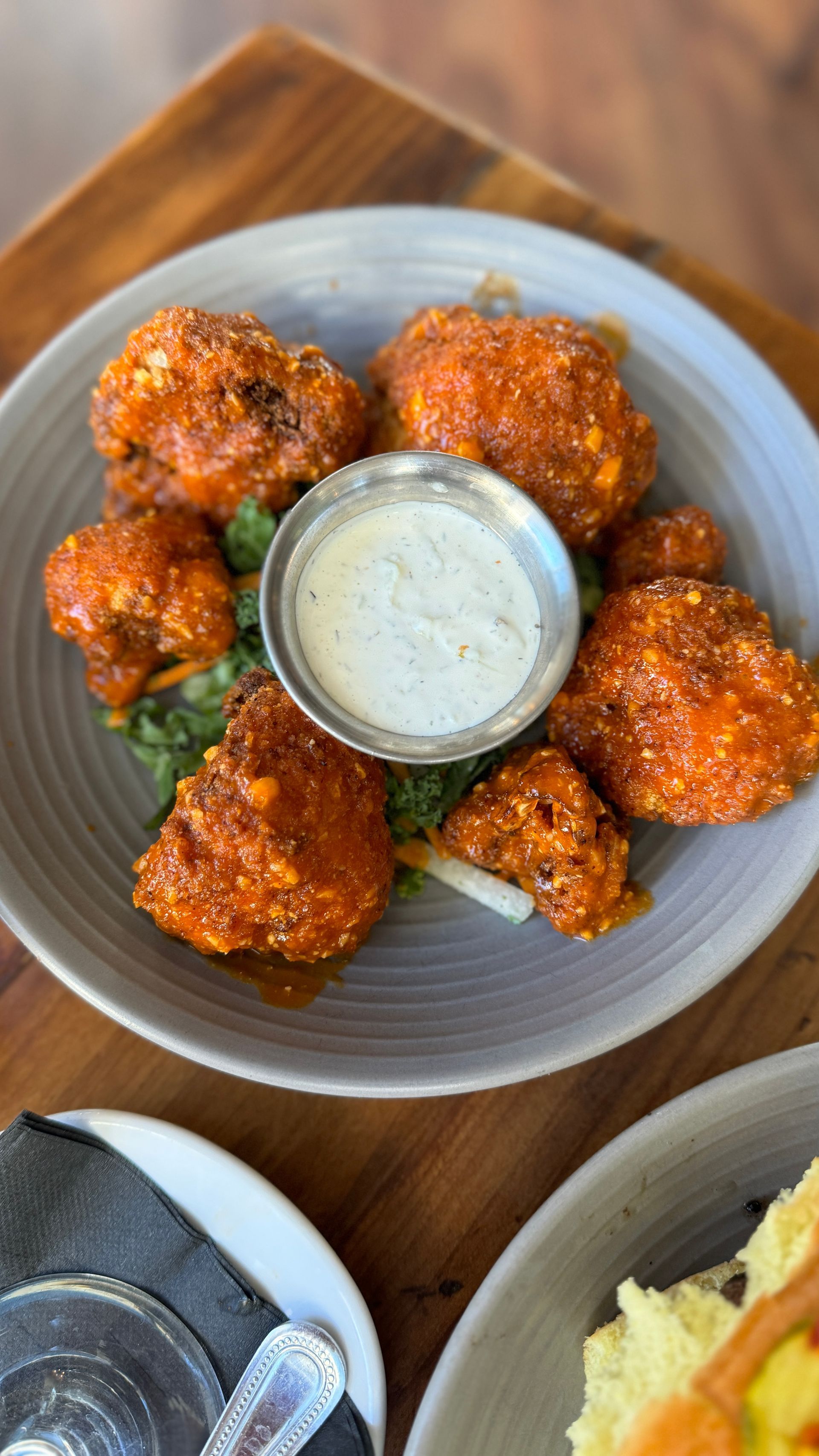 A plate of fried cauliflower wings with ranch dressing on a wooden table.