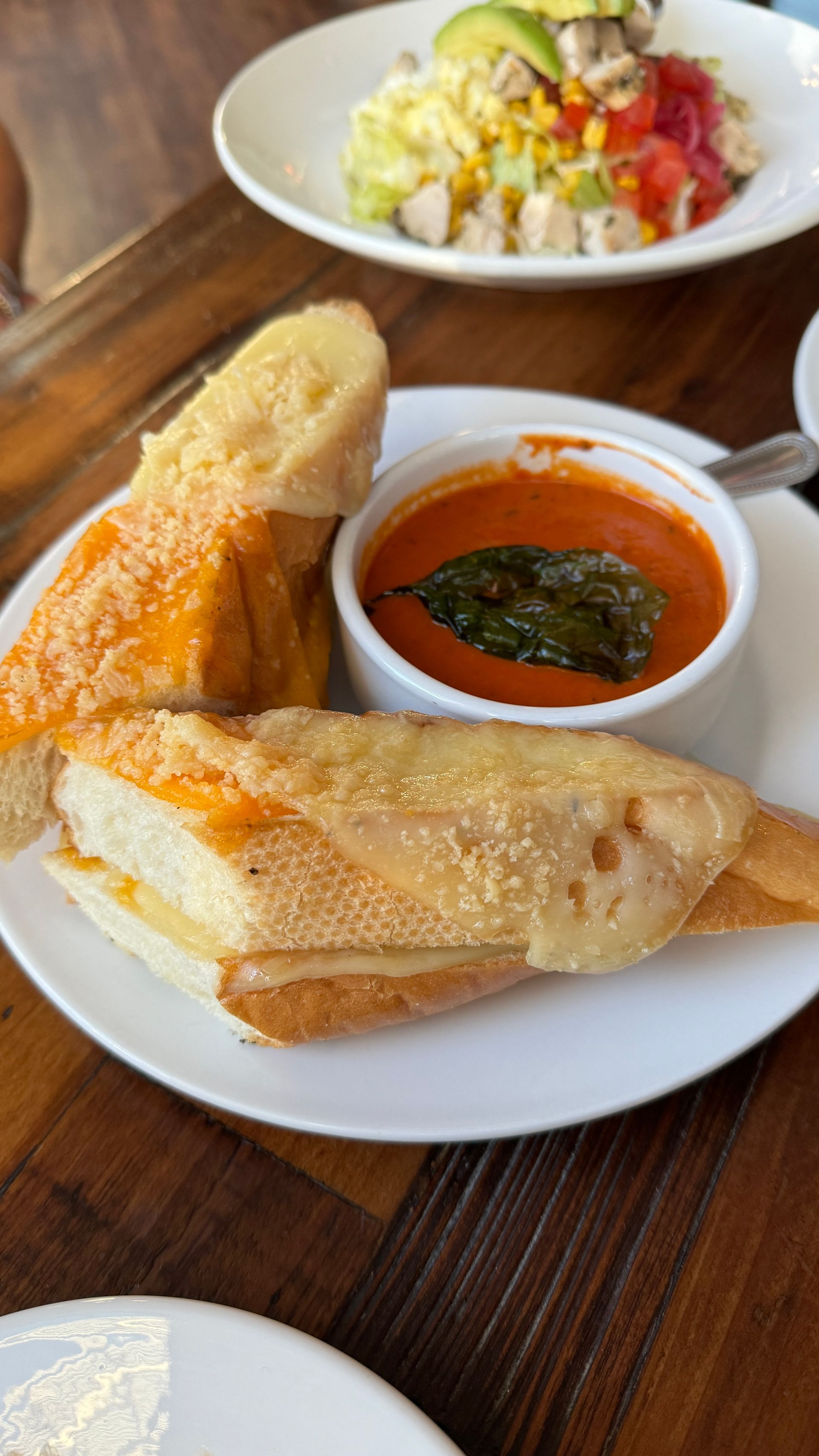 A plate of food with bread and a bowl of soup on a table.