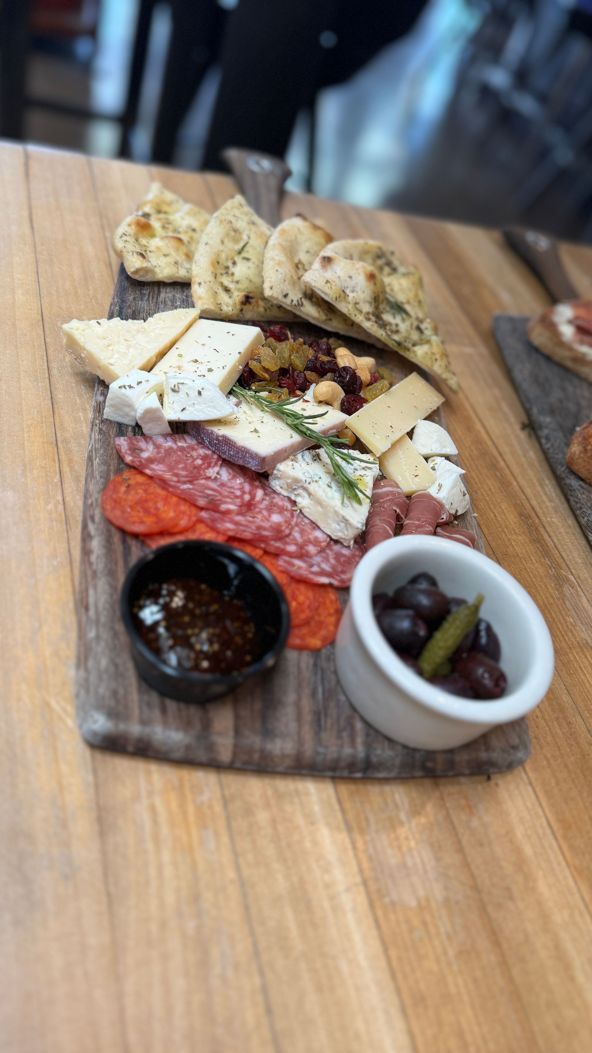 A wooden cutting board topped with a variety of meats and cheeses on a wooden table.
