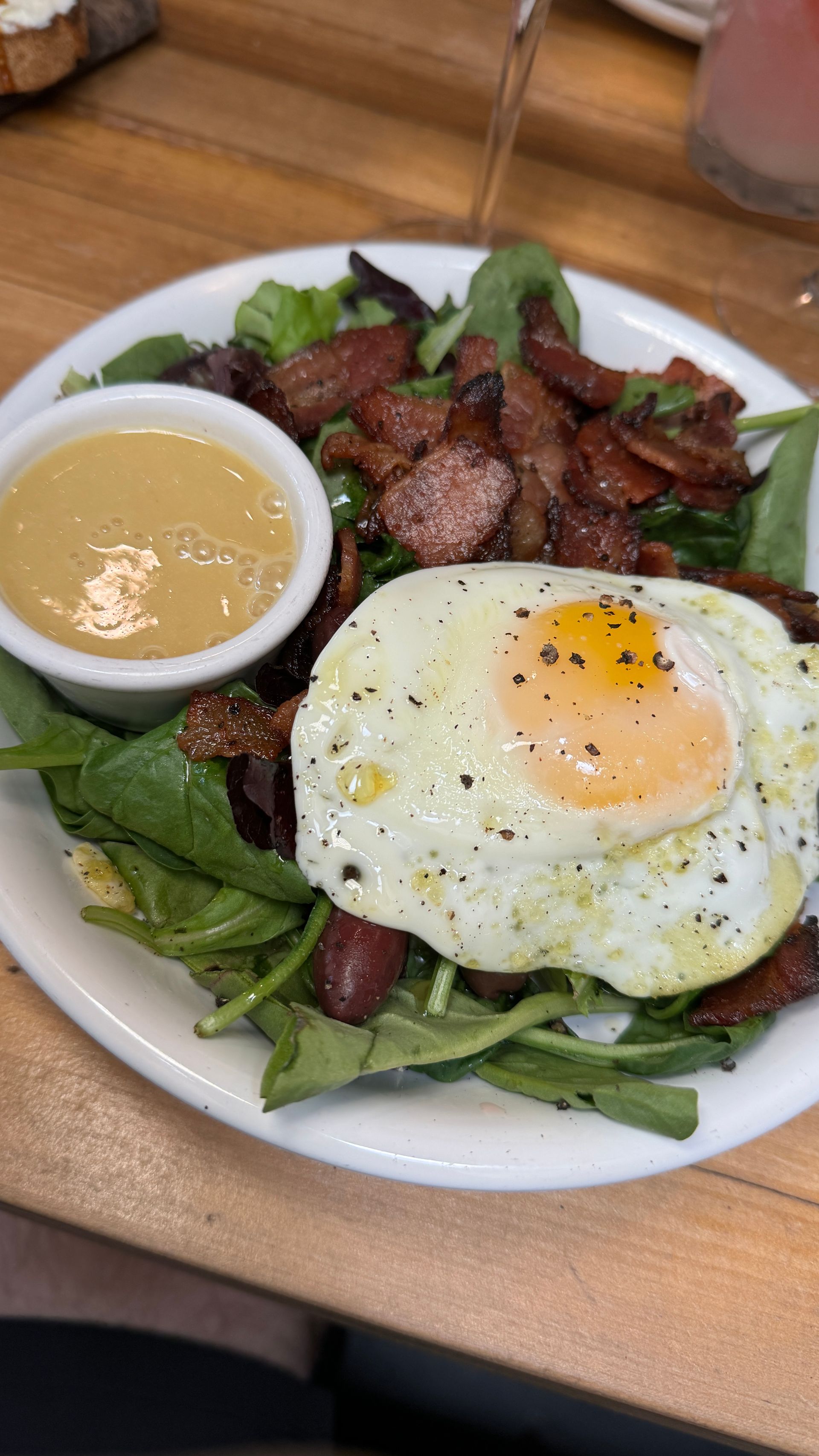 A plate of food with eggs , bacon , lettuce and sauce on a table.
