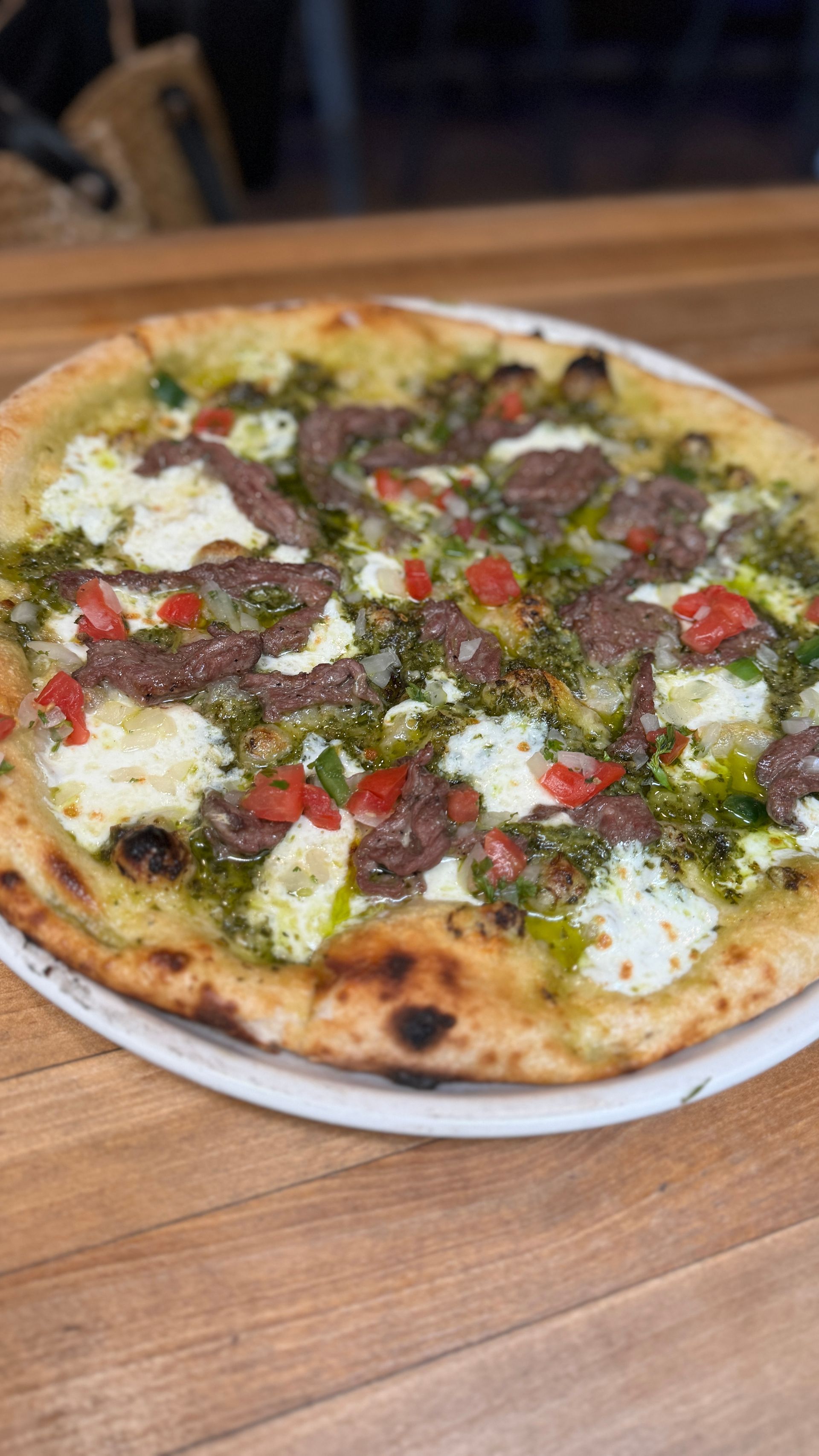 A pizza is sitting on a white plate on a wooden table.