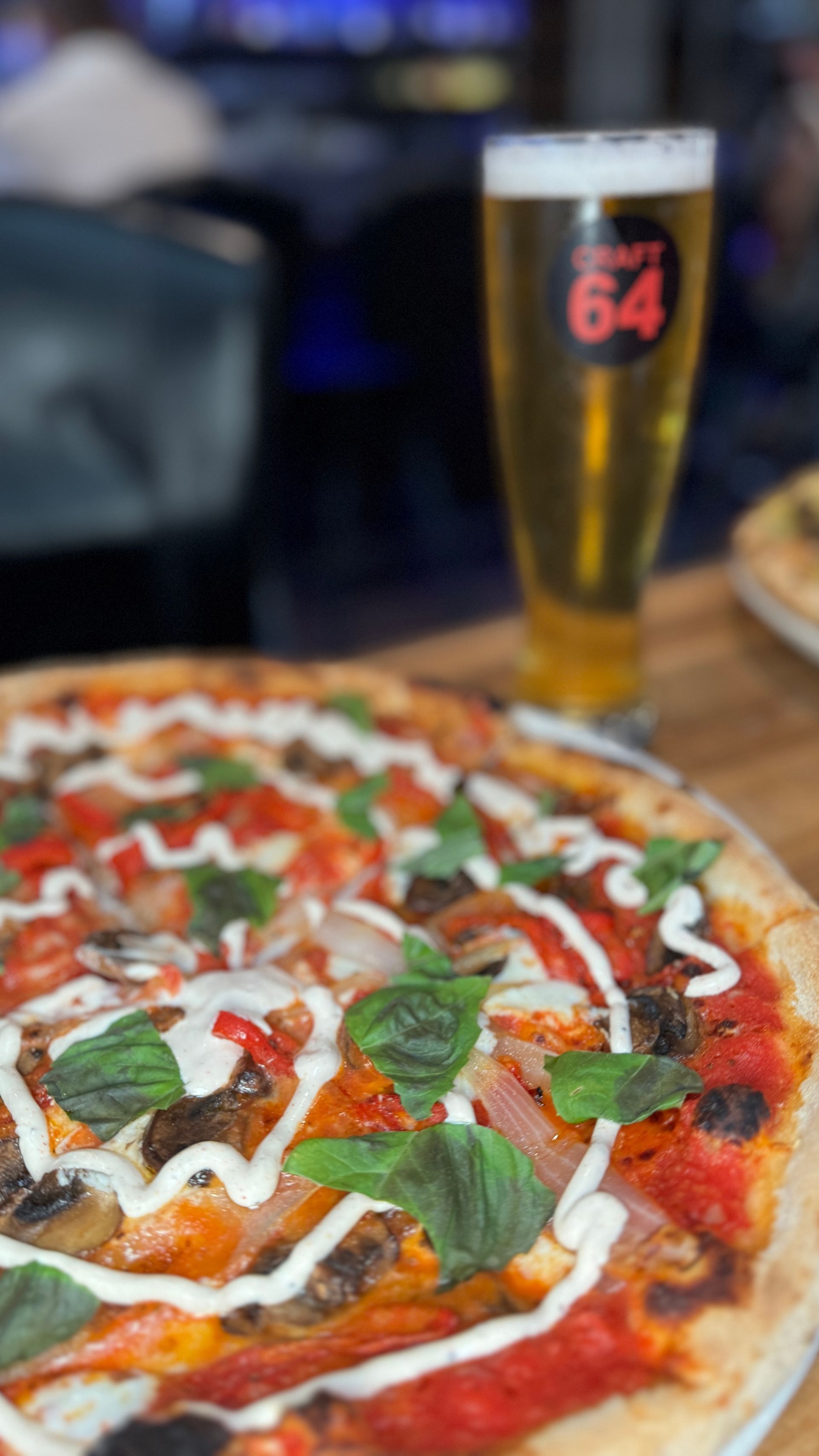 A pizza and a glass of beer are on a table.