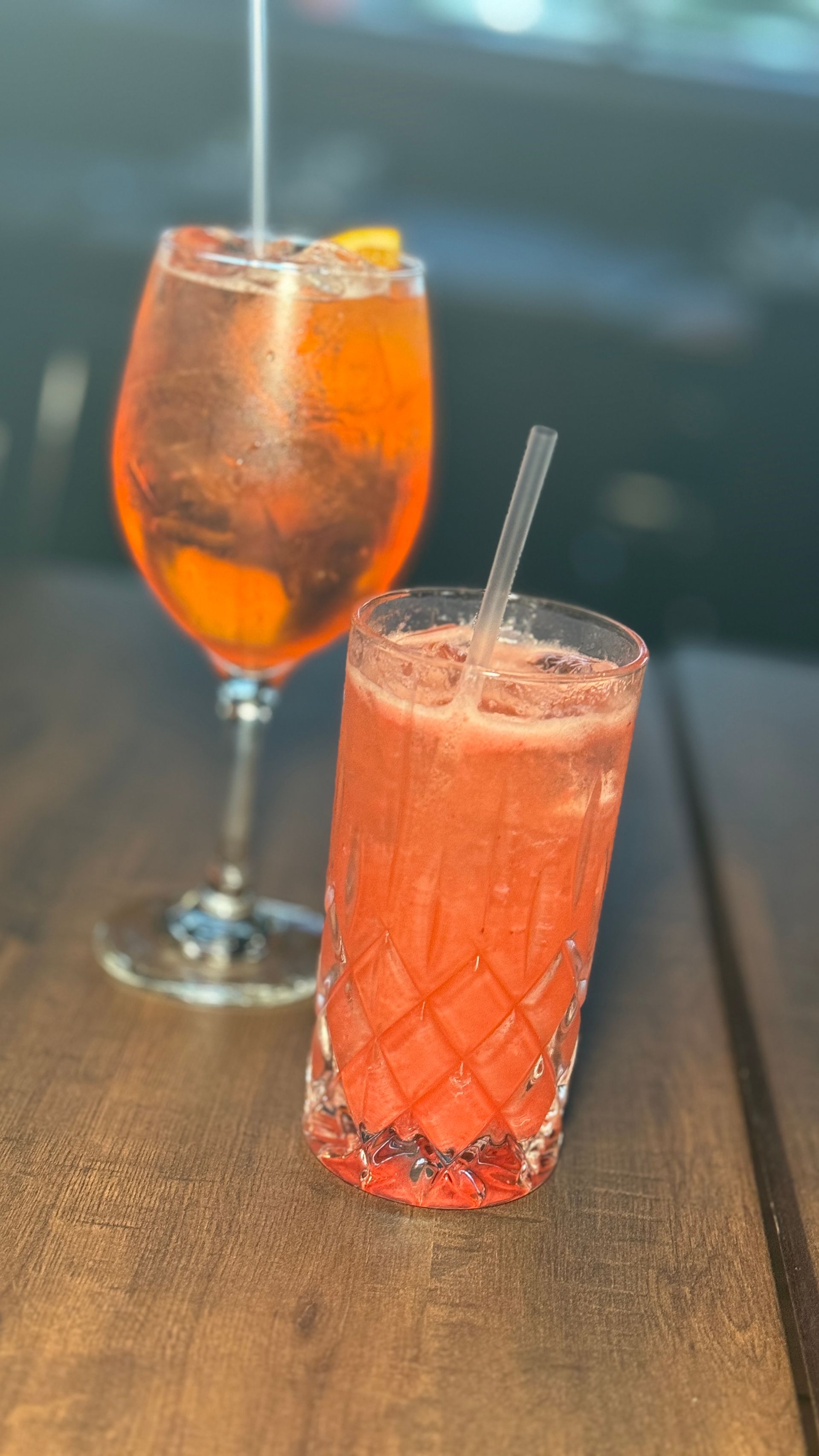 Two drinks are sitting on a wooden table next to each other.