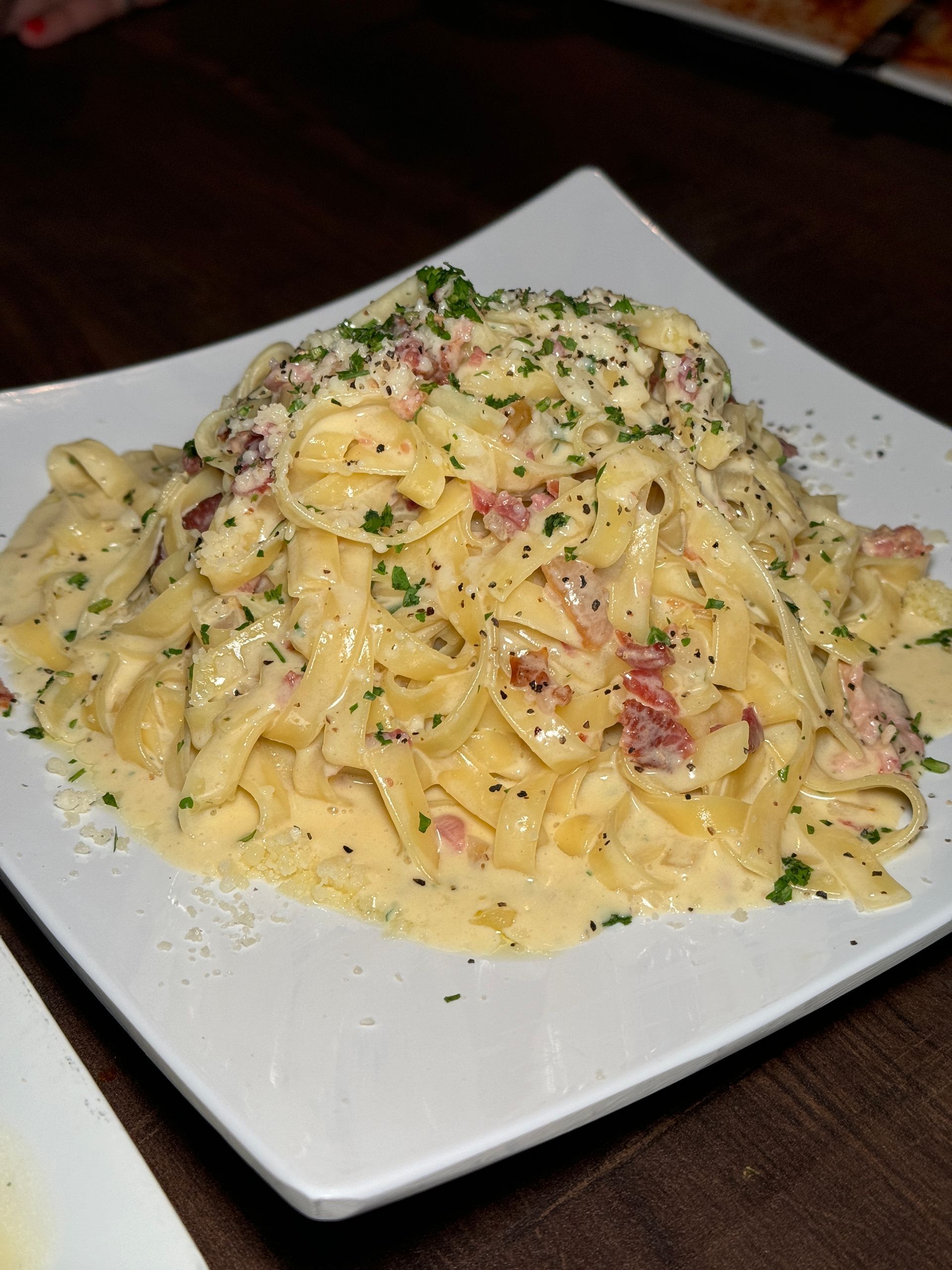 A white plate topped with pasta and sauce on a table.