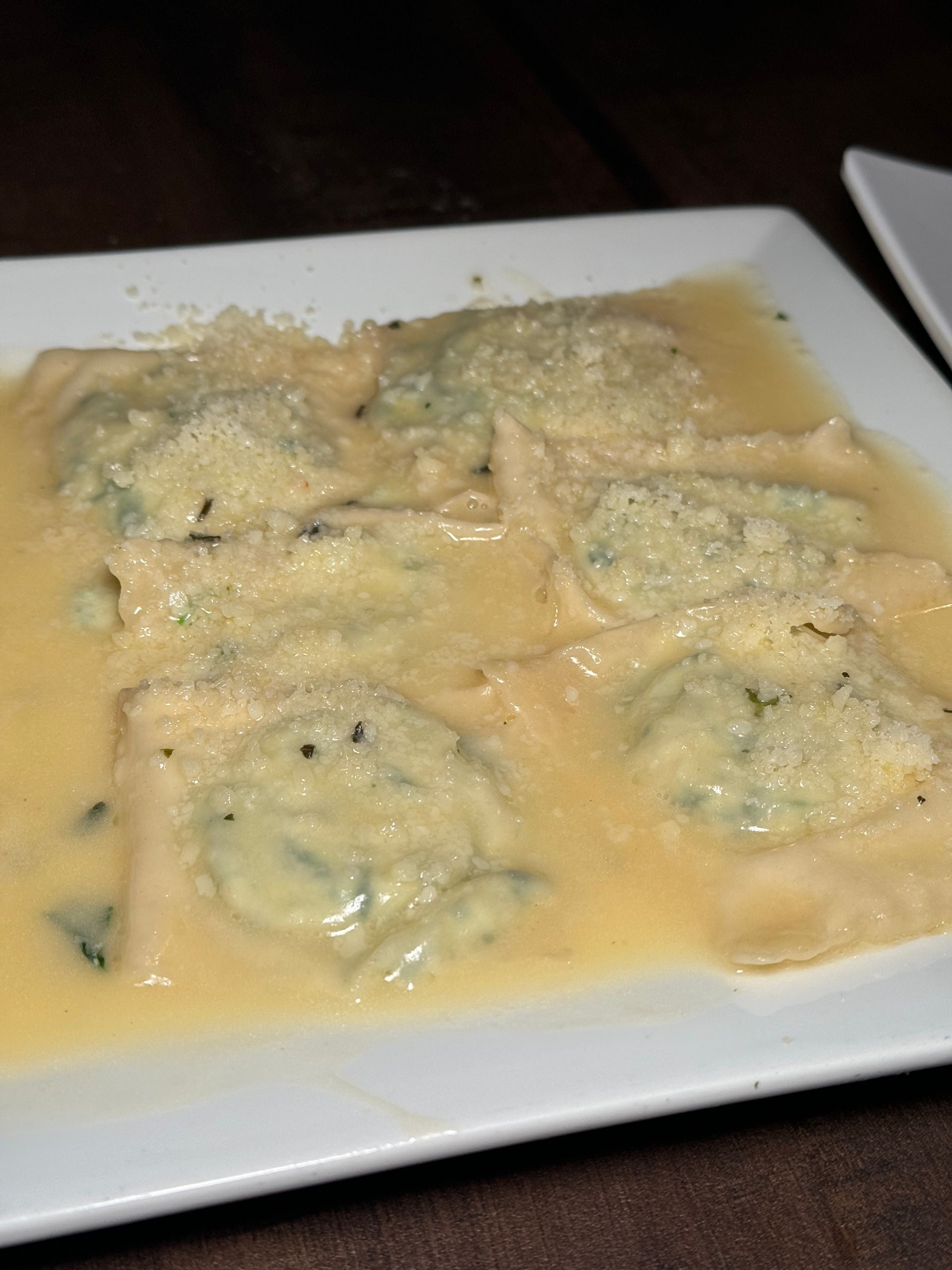 A white plate topped with ravioli and sauce on a table.