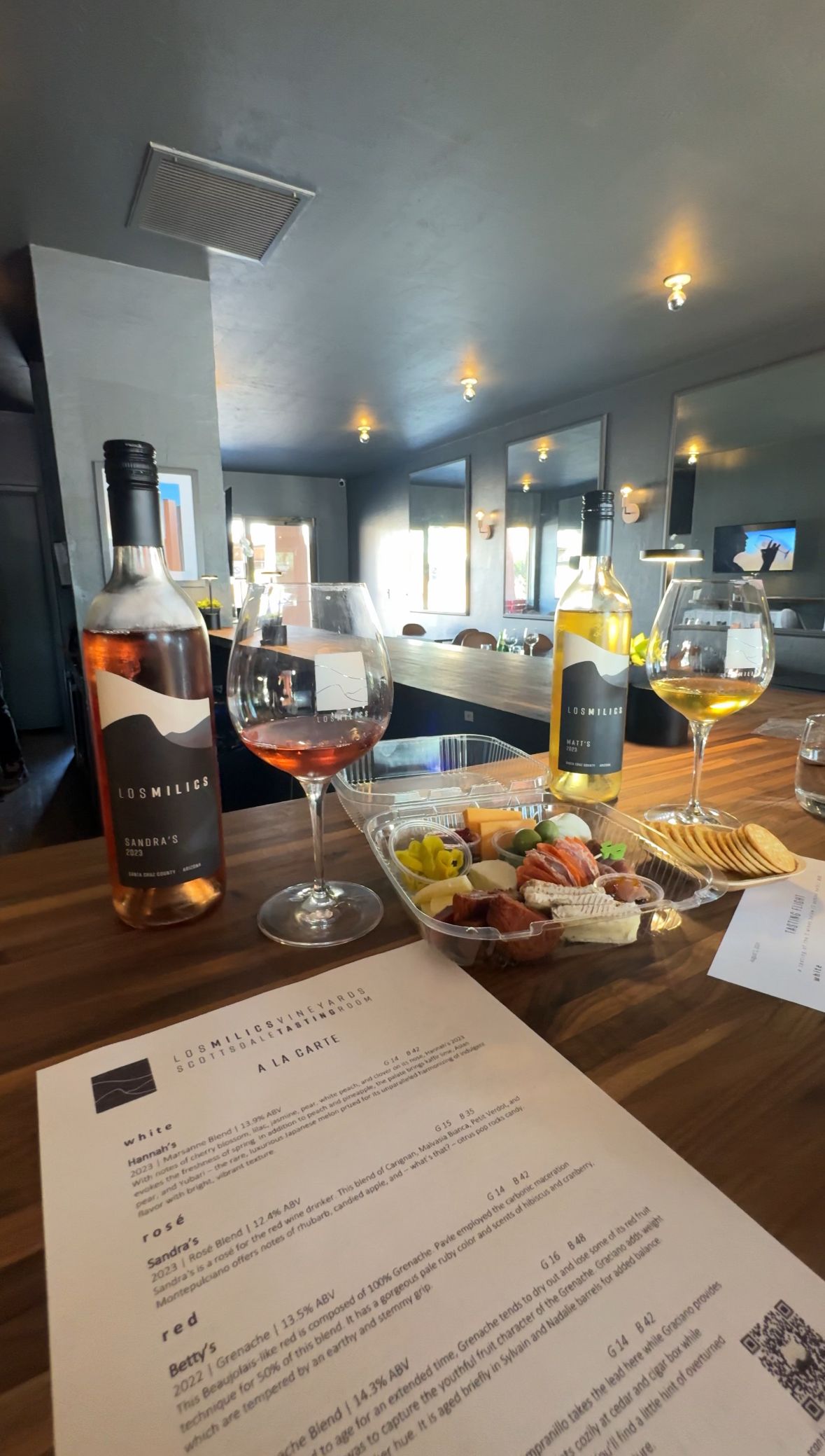 A table with a bottle of wine , a glass of wine , and a plate of food.