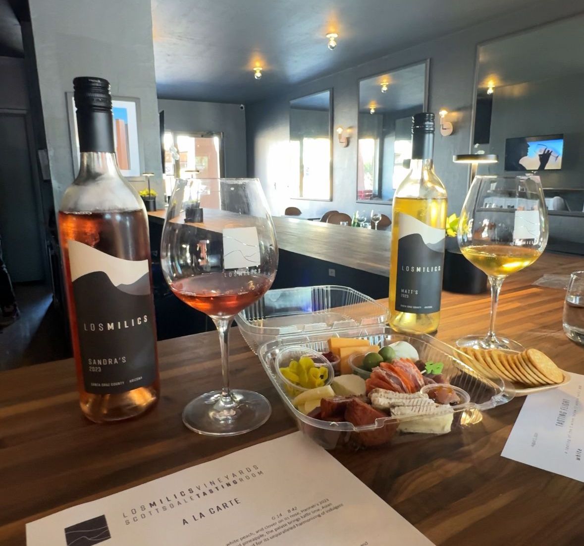 A bottle of wine sits on a table next to two glasses of wine