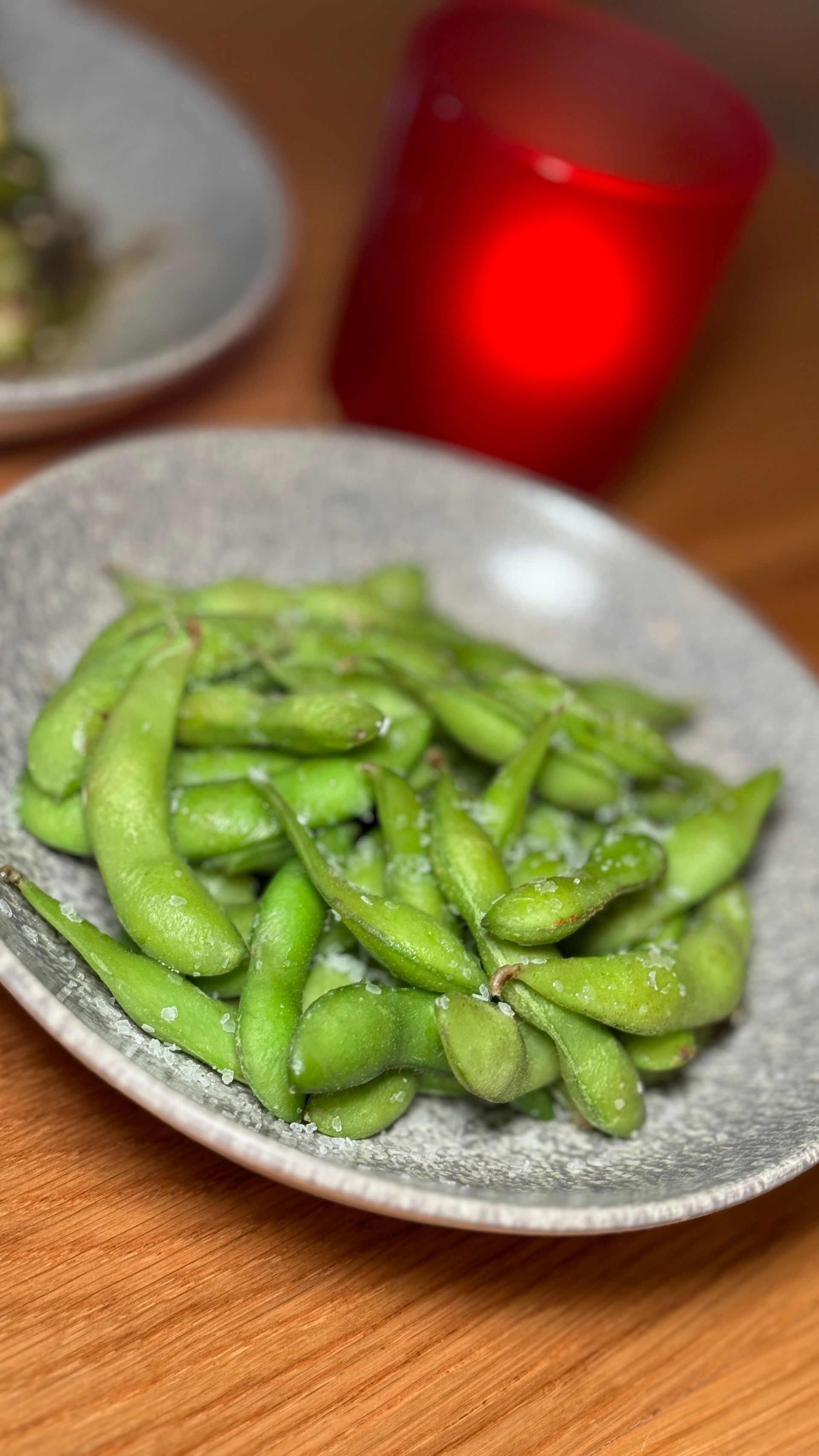 A close up of a plate of green beans on a wooden table.