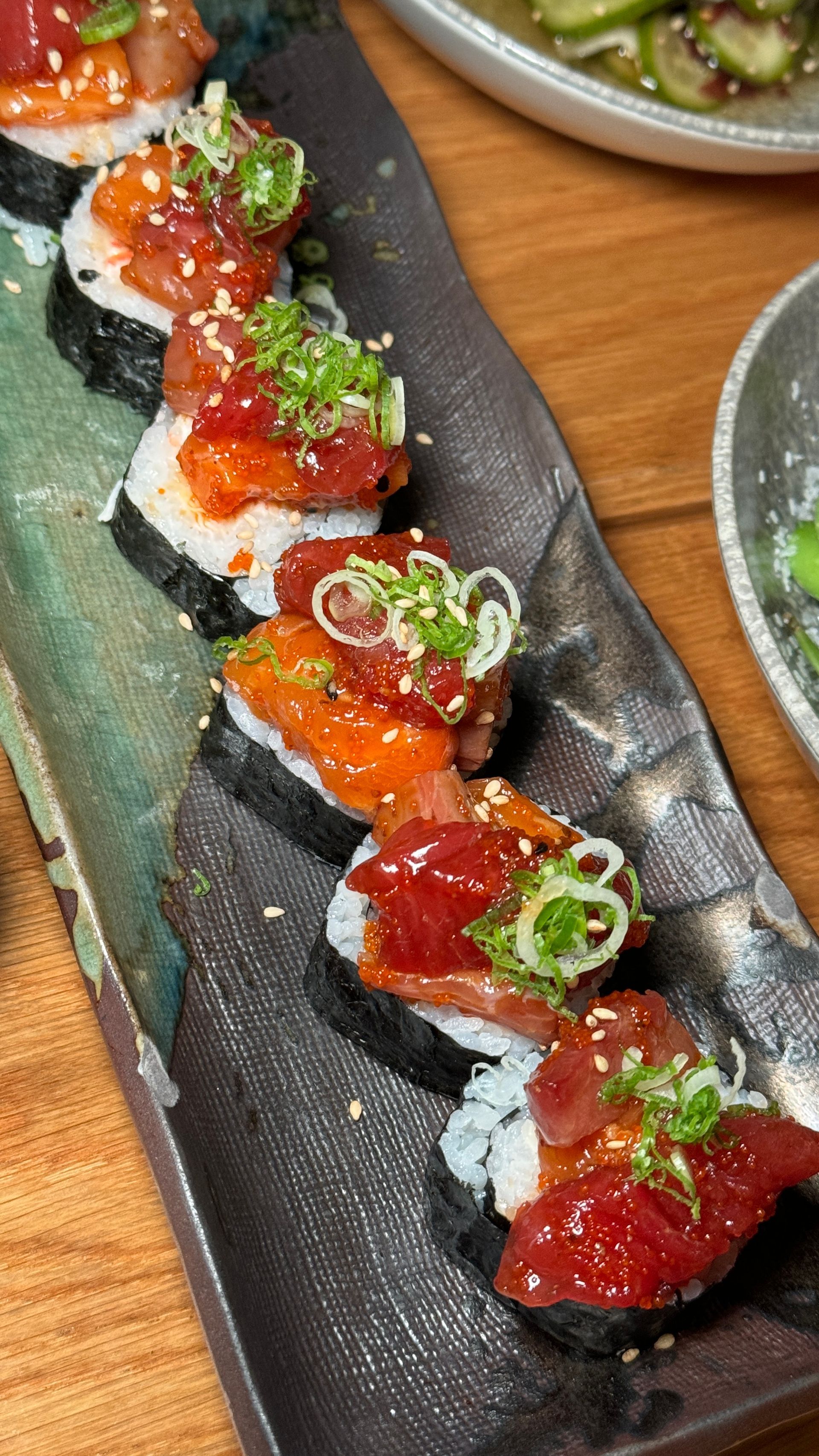 A close up of a plate of sushi on a wooden table.