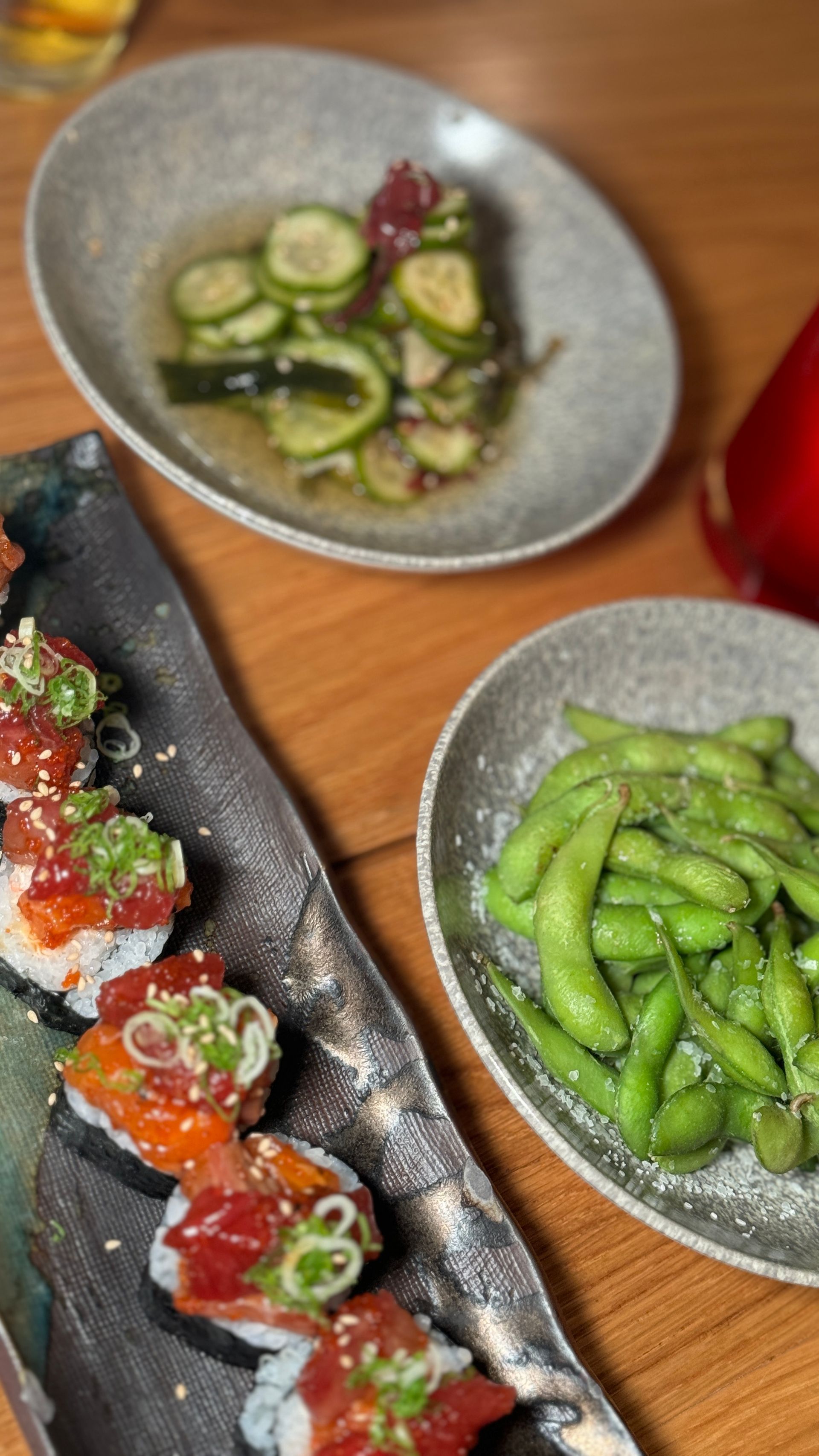 A table topped with plates of sushi and edamame beans.