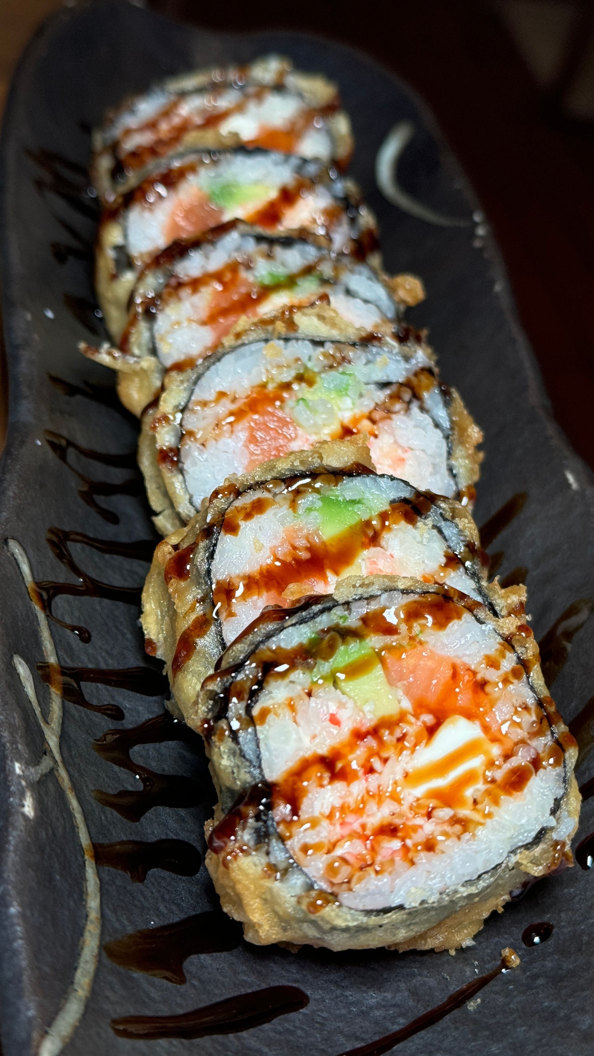 A close up of a fried sushi roll on a plate.