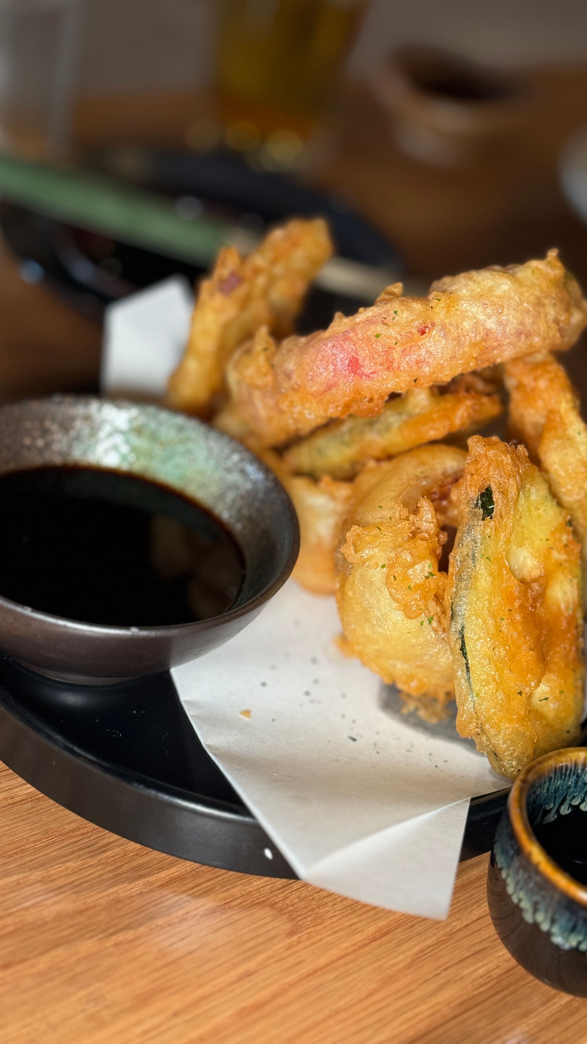 A close up of a plate of food with a bowl of dipping sauce on a table.