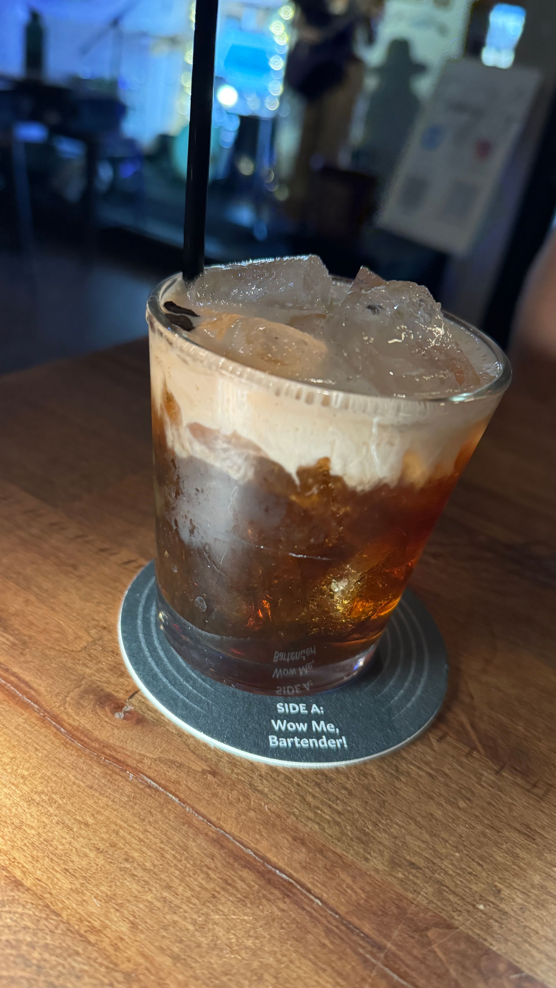 A close up of a drink on a coaster on a wooden table.