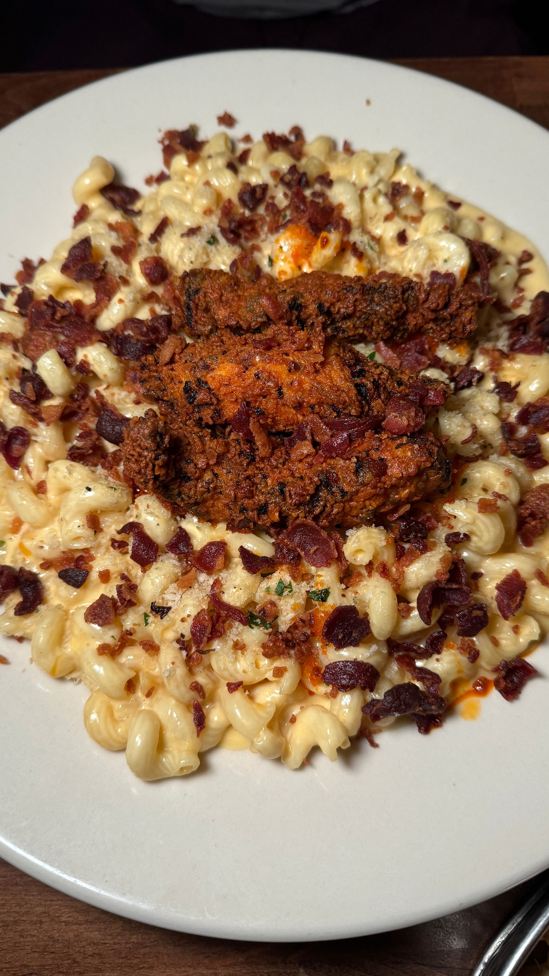 A white plate topped with macaroni and cheese and bacon.
