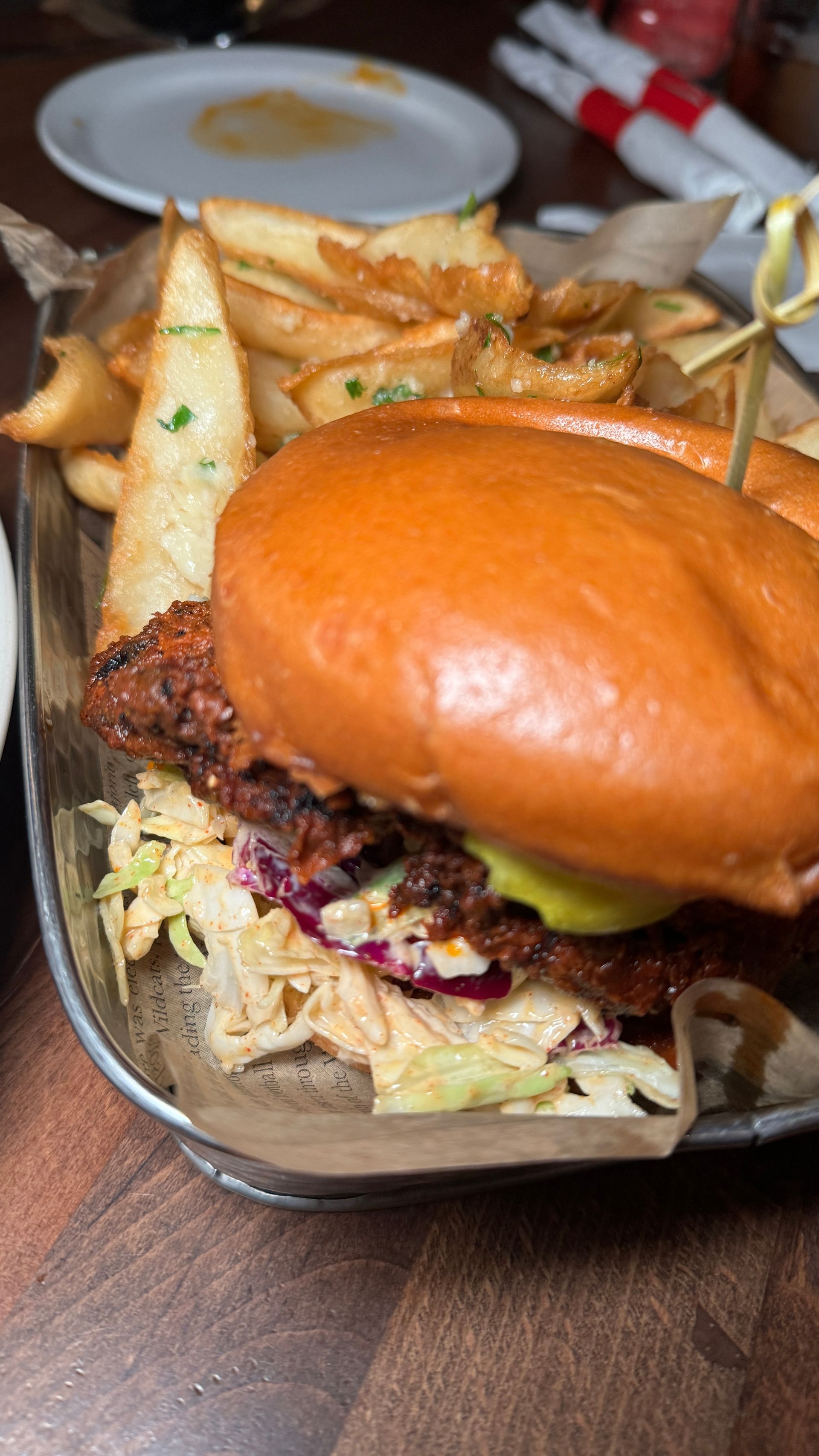 A close up of a chicken sandwich and french fries on a tray on a table.