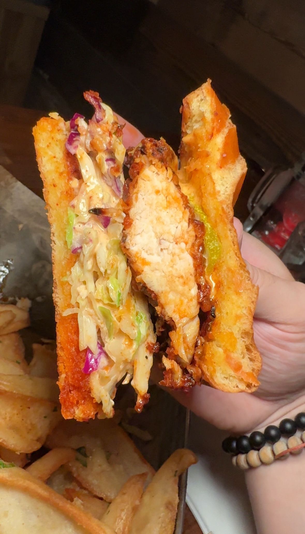 A person is holding a fried chicken sandwich in their hand.