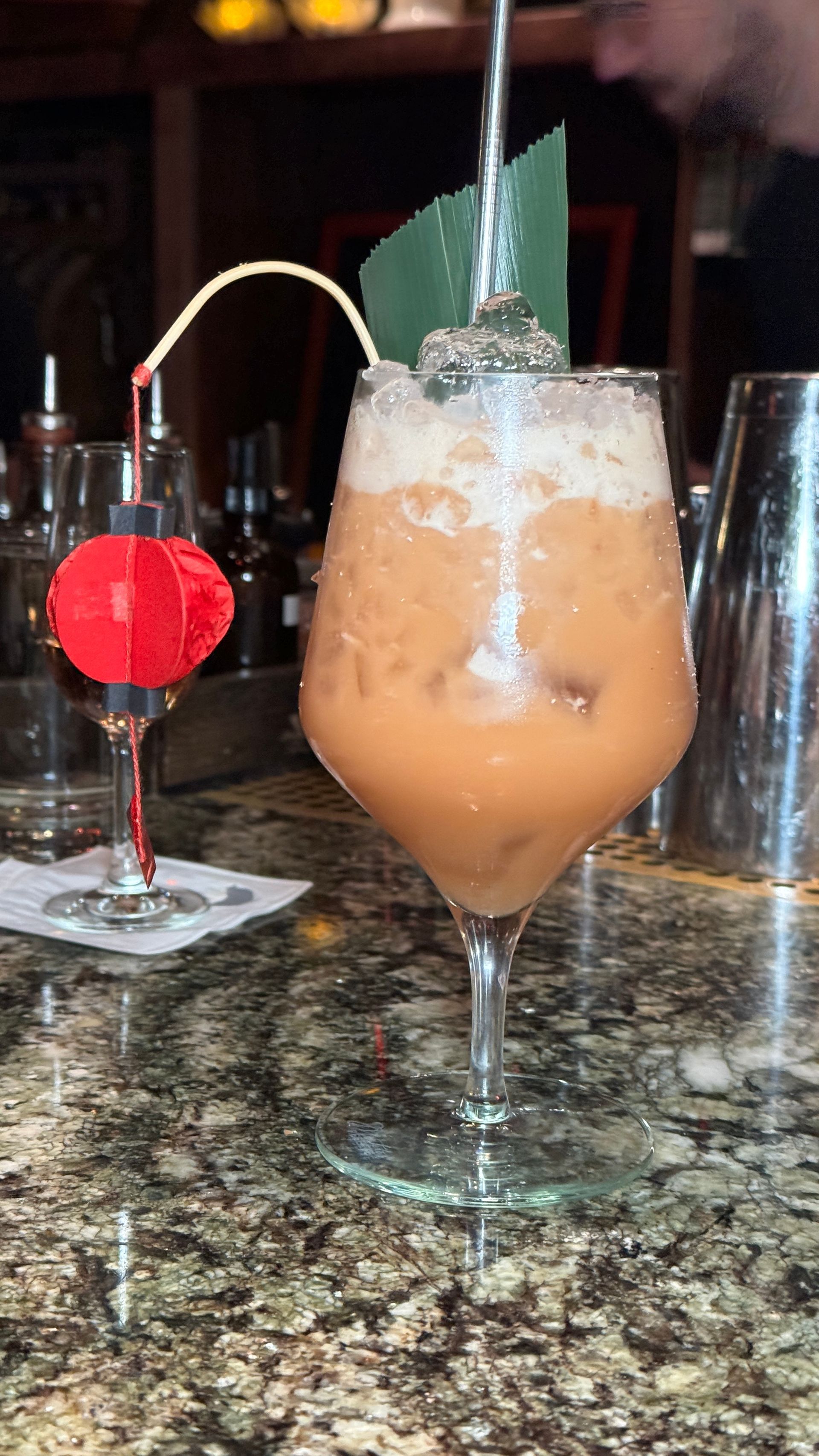 A bartender is pouring a drink into a glass on a counter.