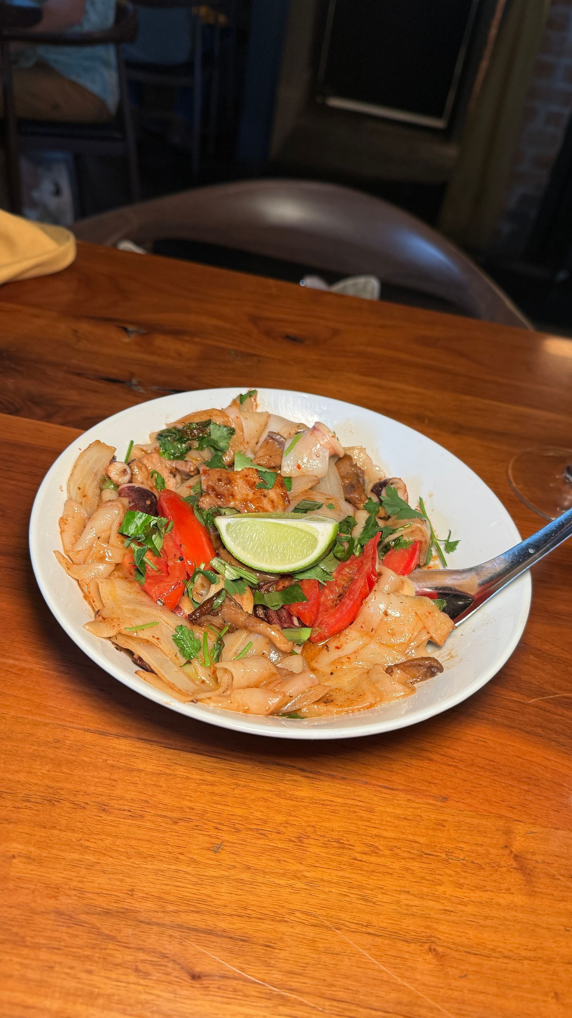 A plate of food with a spoon in it is on a wooden table.