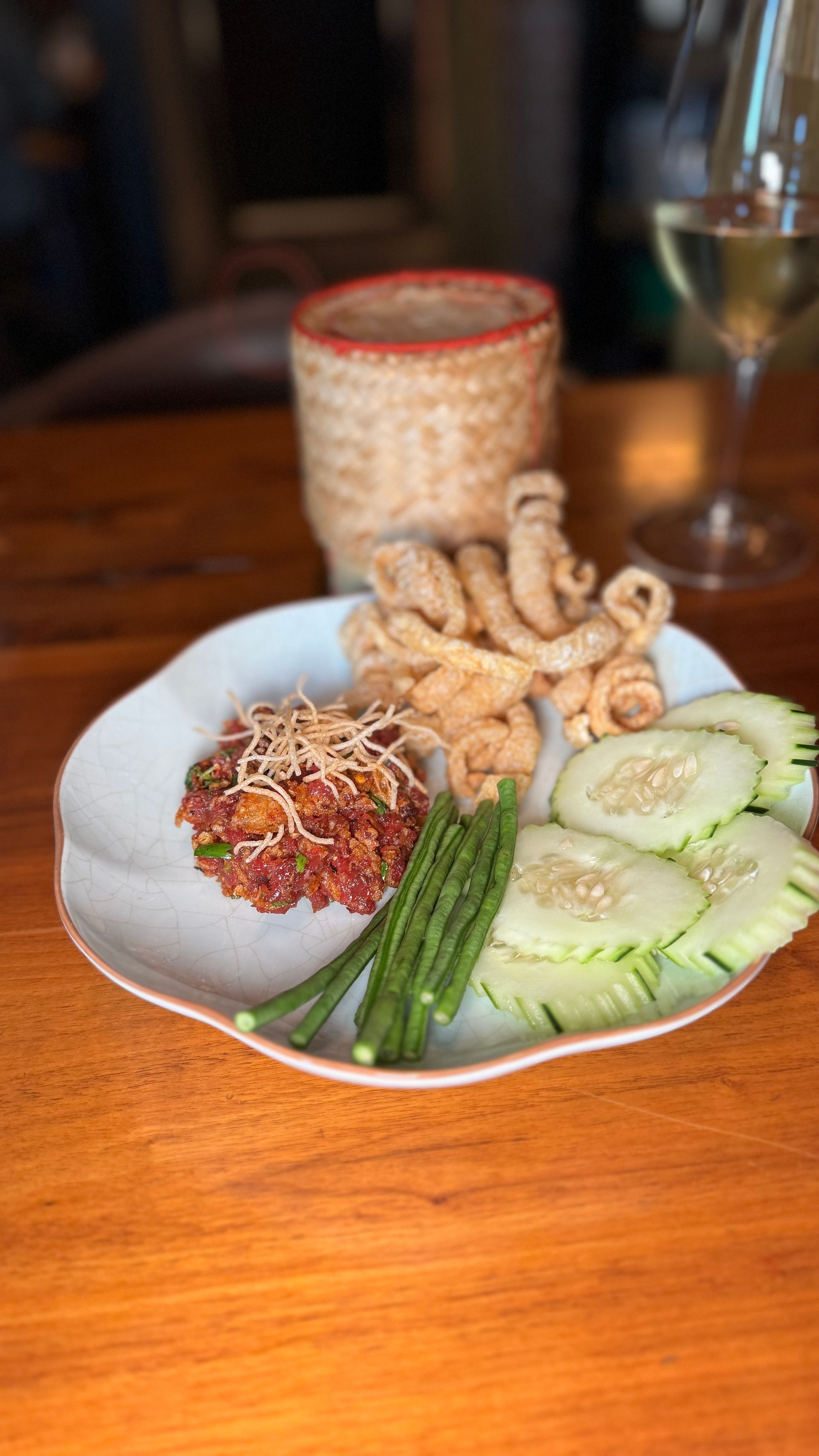 A plate of food with vegetables and a glass of wine on a wooden table.