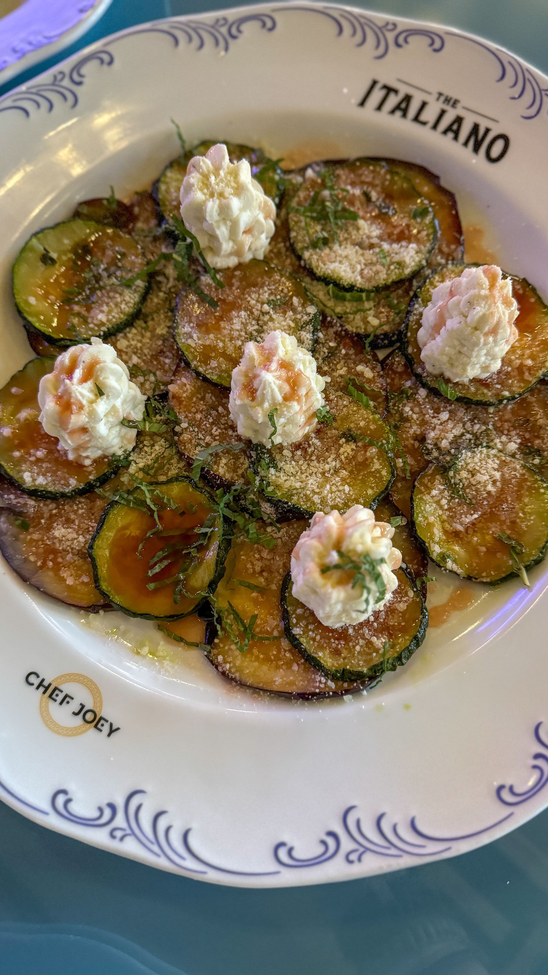 A white plate topped with sliced zucchini and whipped cream.