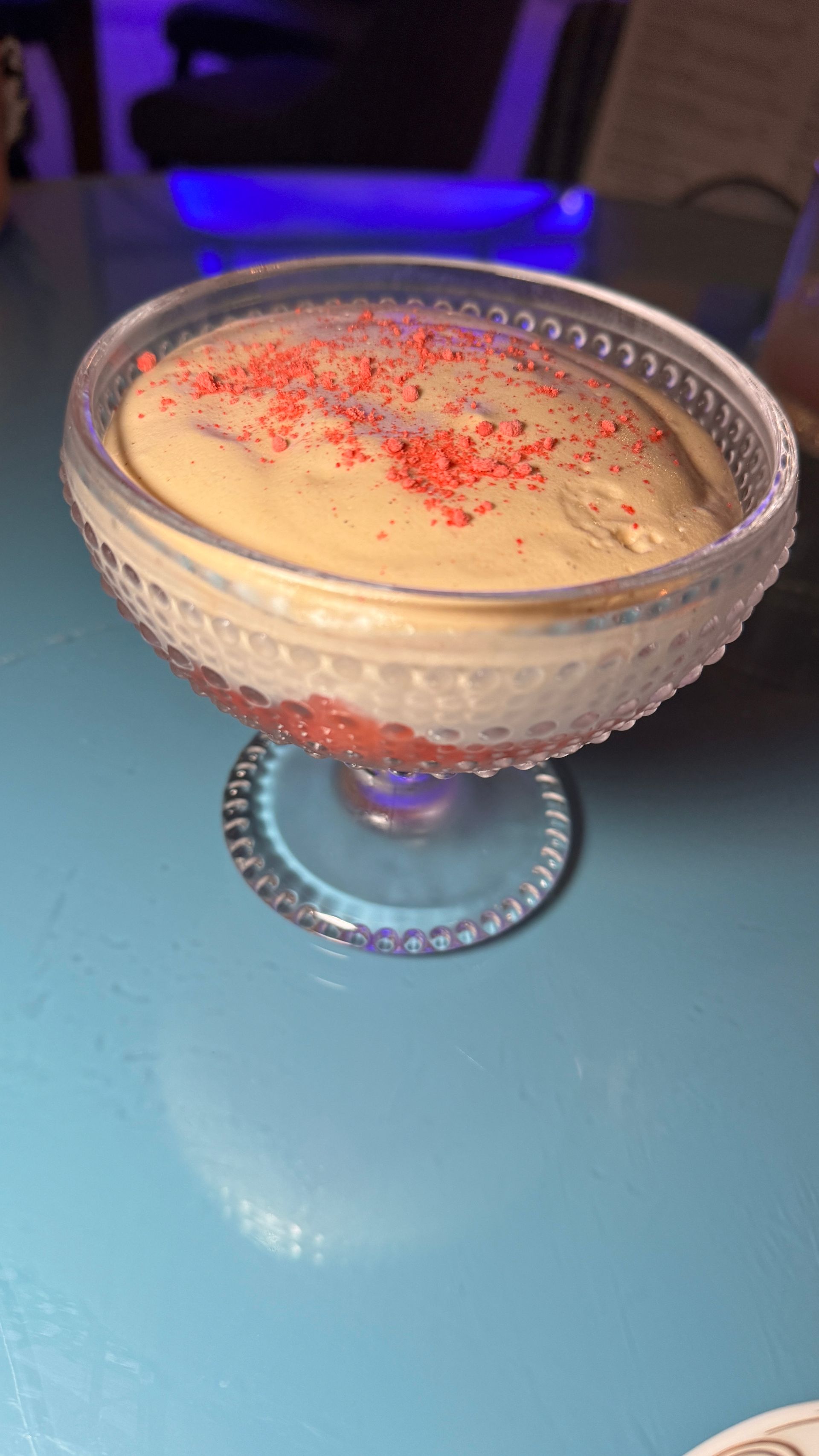 A close up of a dessert in a glass on a table.