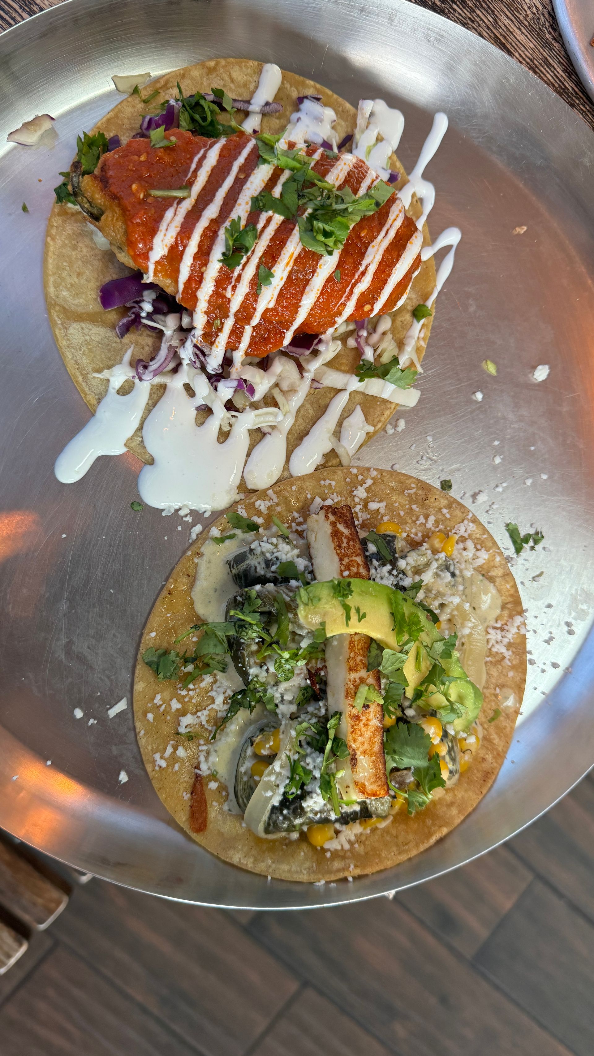 A close up of two tacos on a plate on a table.