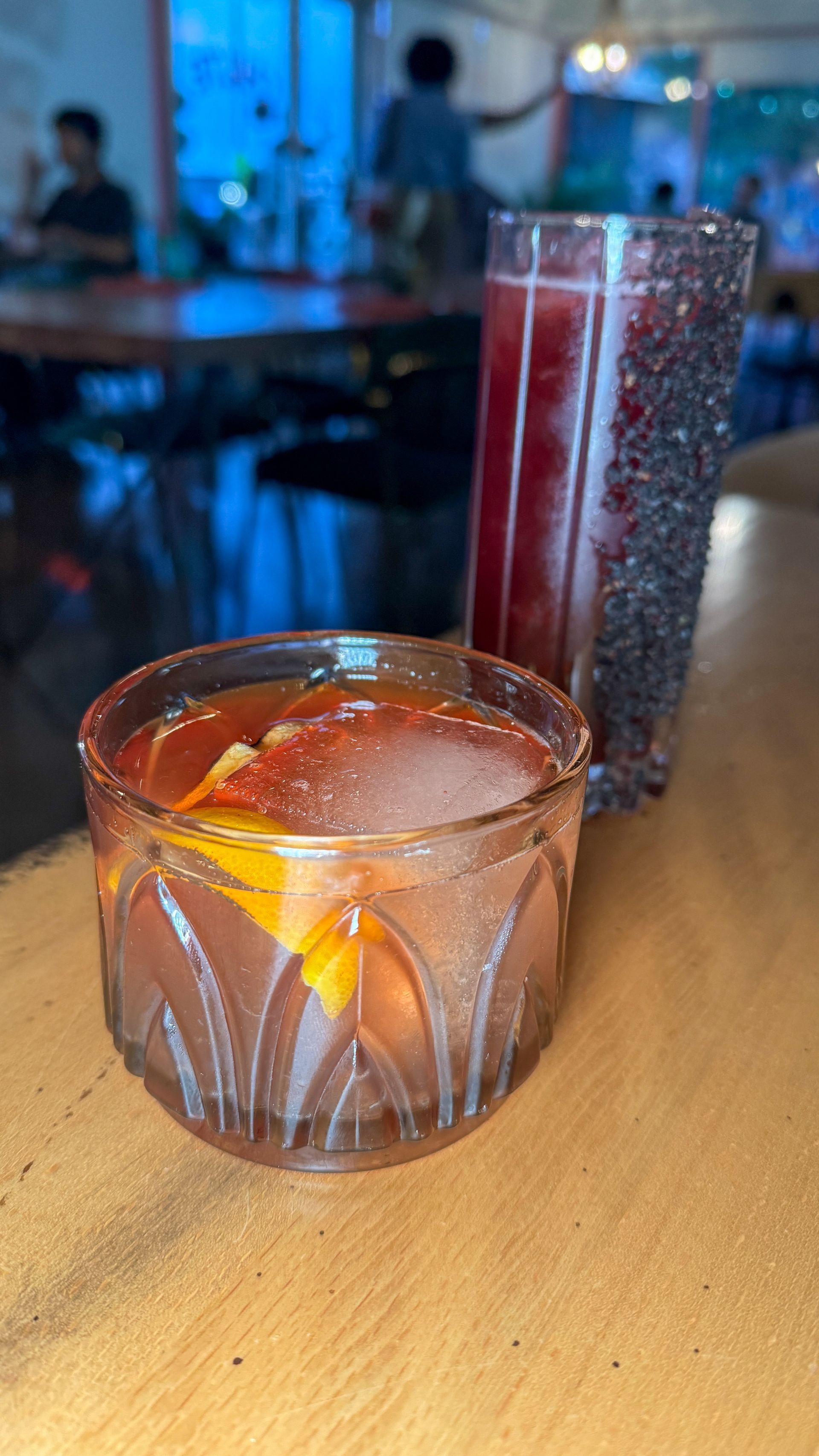Two glasses of drinks are sitting on a wooden table.