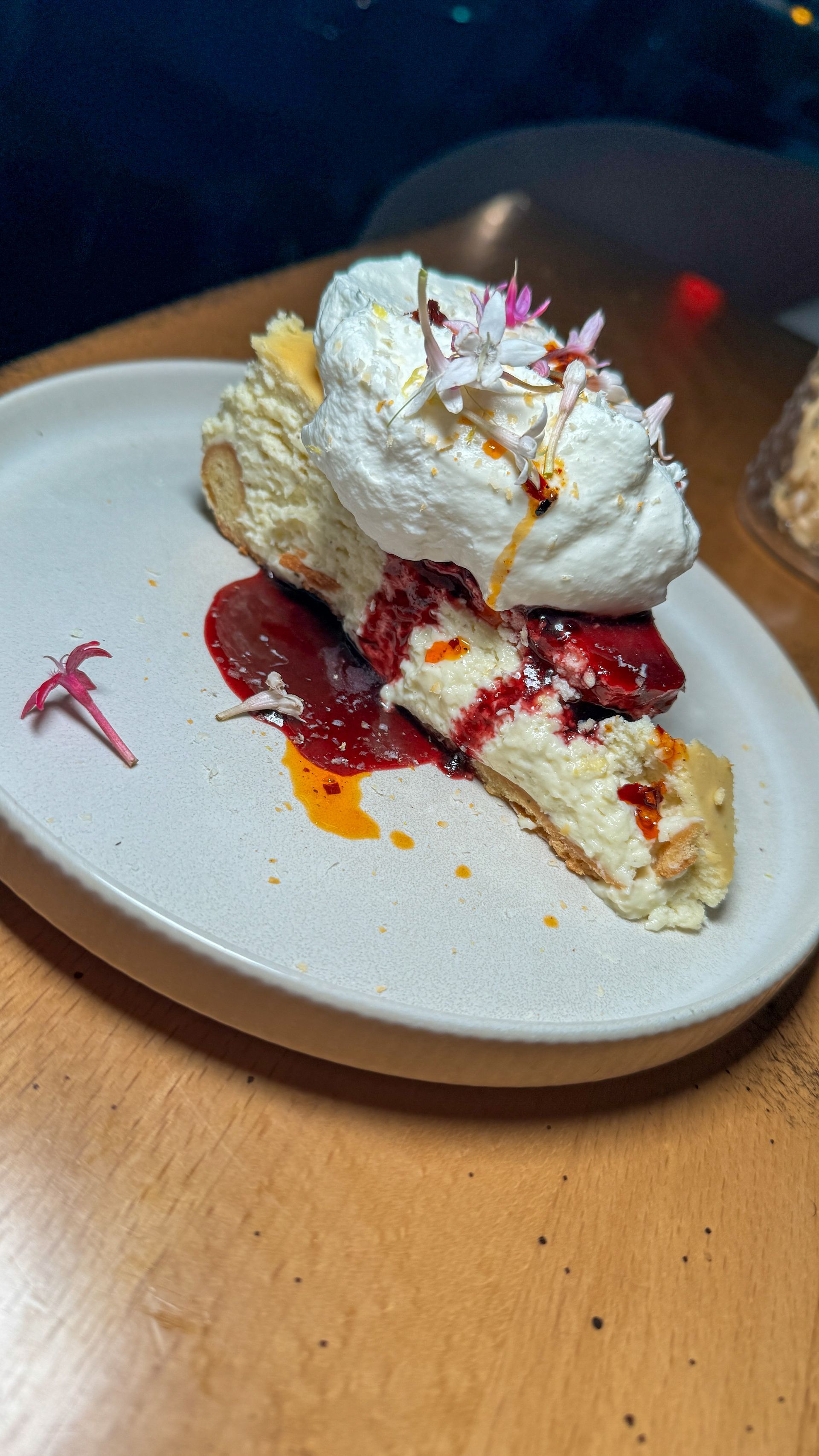 A slice of cheesecake on a white plate on a wooden table.