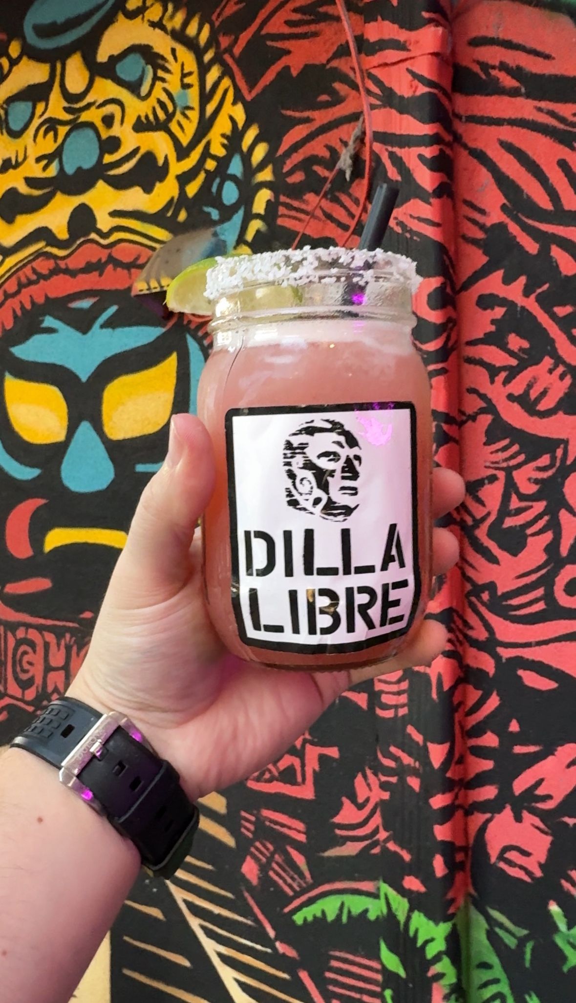 A person is holding a drink in a jar that says dilla libre