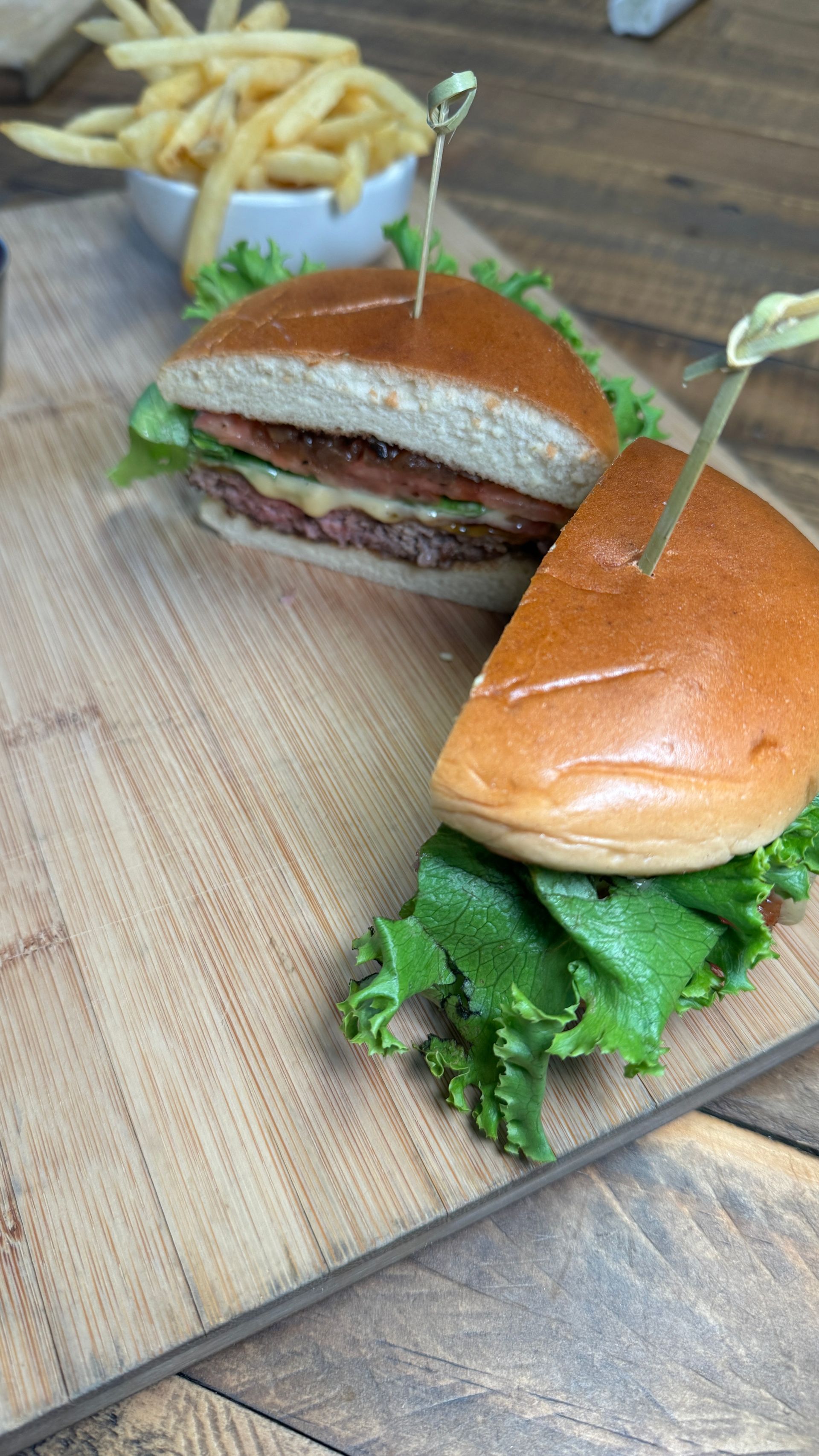 A hamburger and french fries are on a wooden cutting board.