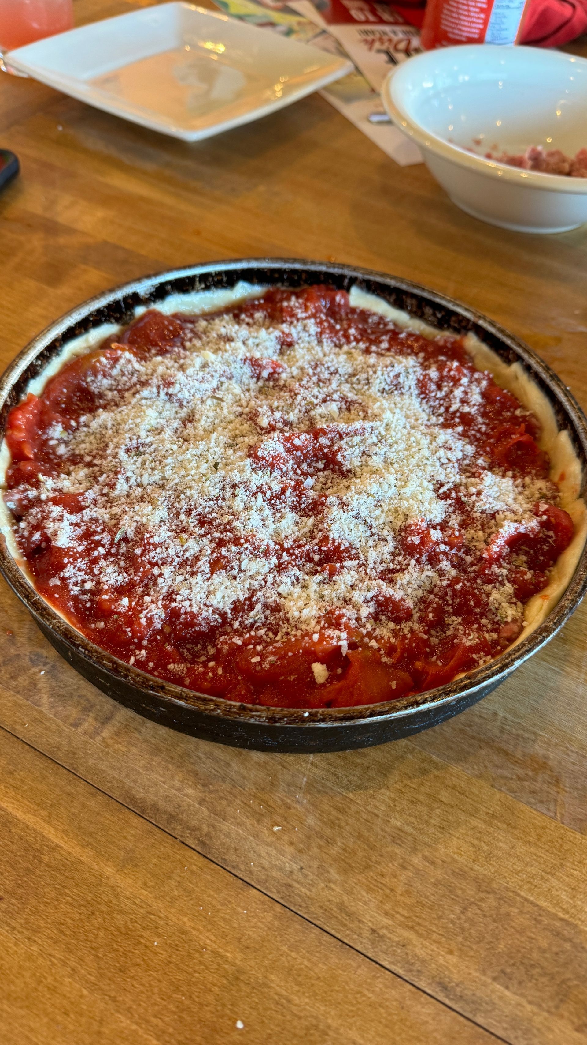 A pizza with tomato sauce and cheese is sitting on a wooden table.