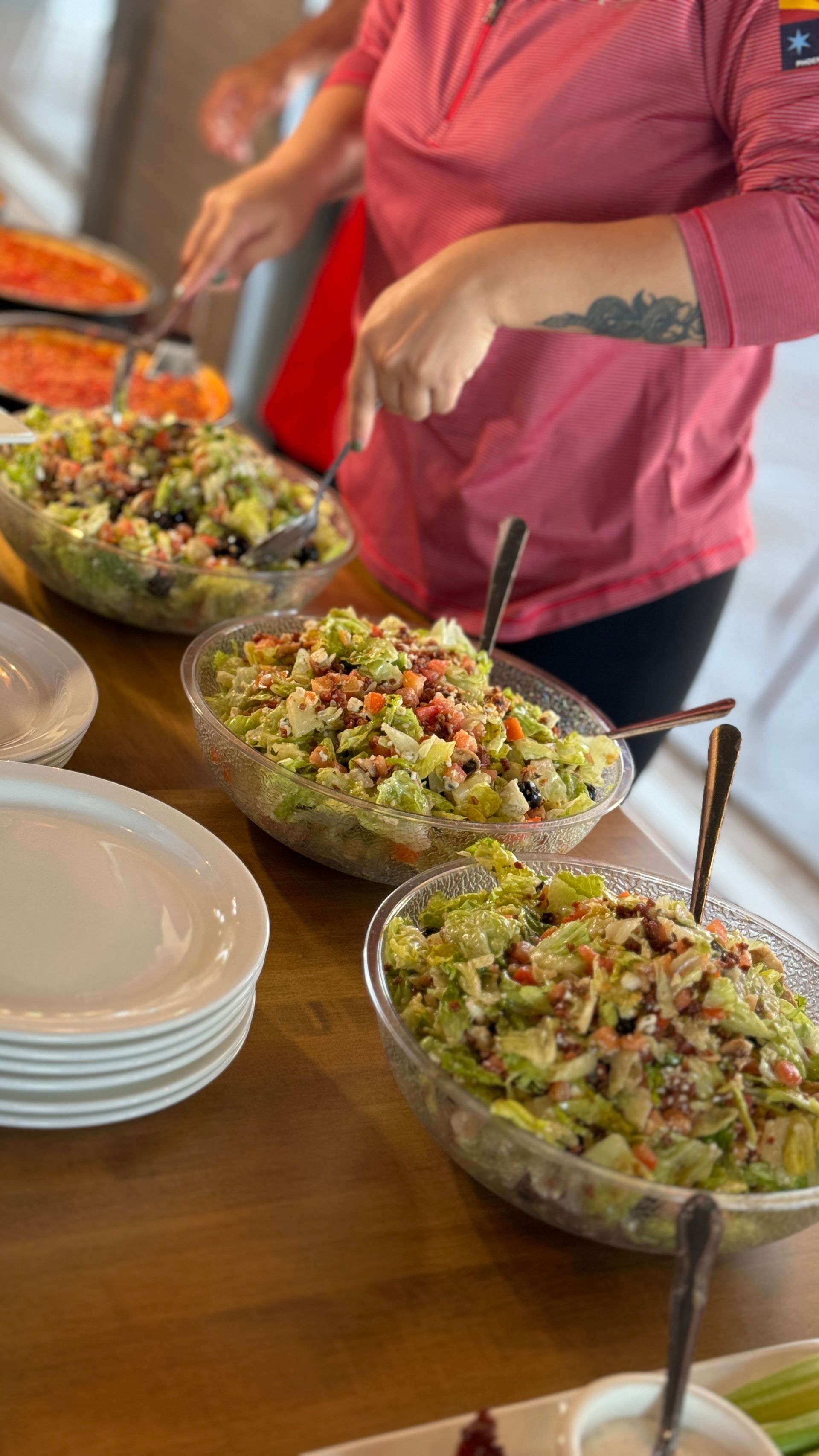 A woman is preparing a salad on a wooden table.