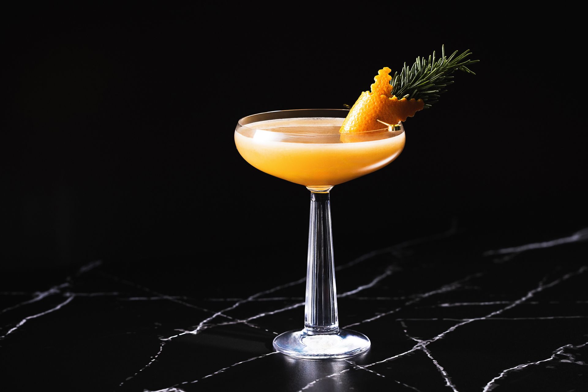 A close up of a cocktail in a coupe glass on a table.