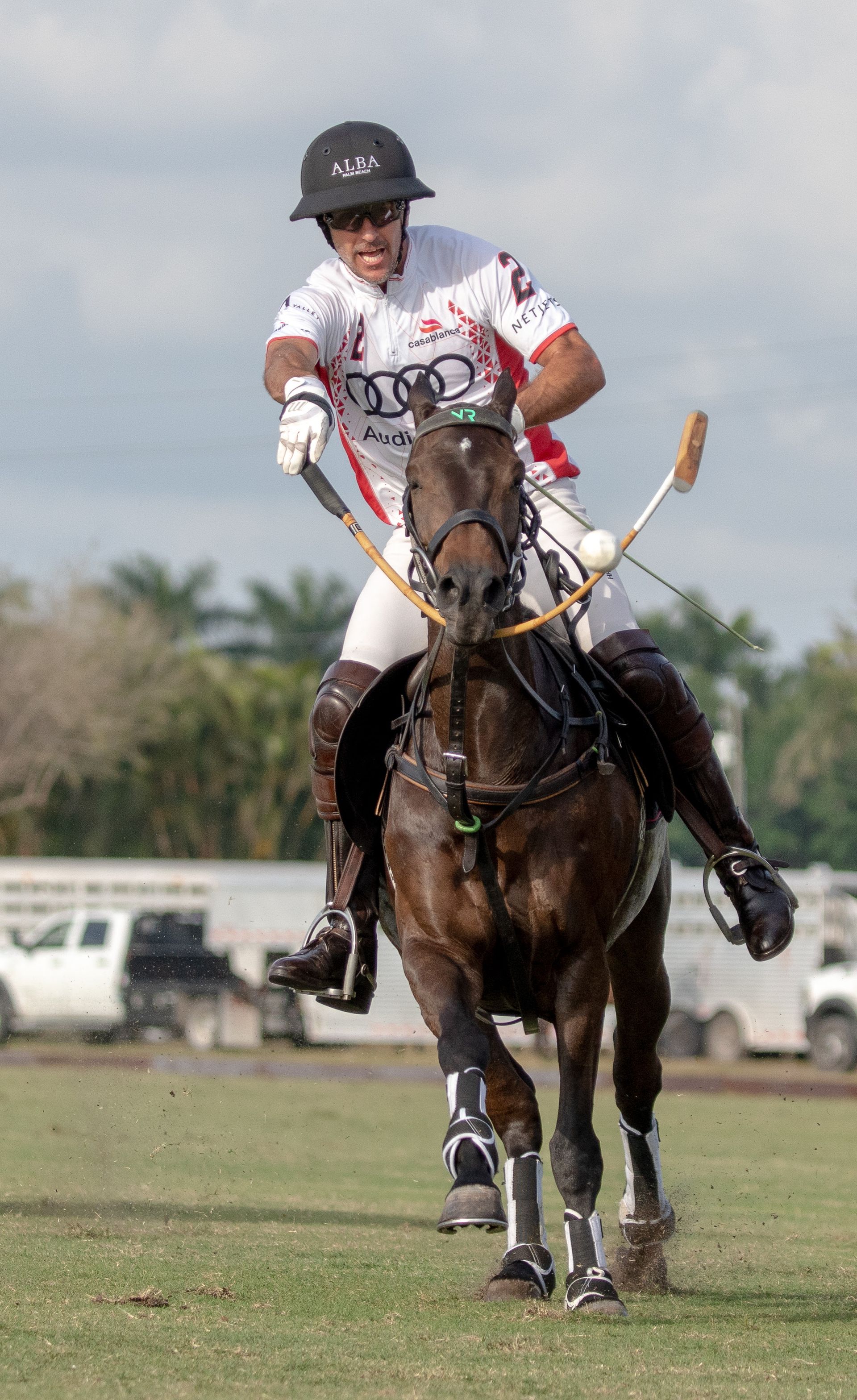 A man is riding a horse on a field while playing polo.