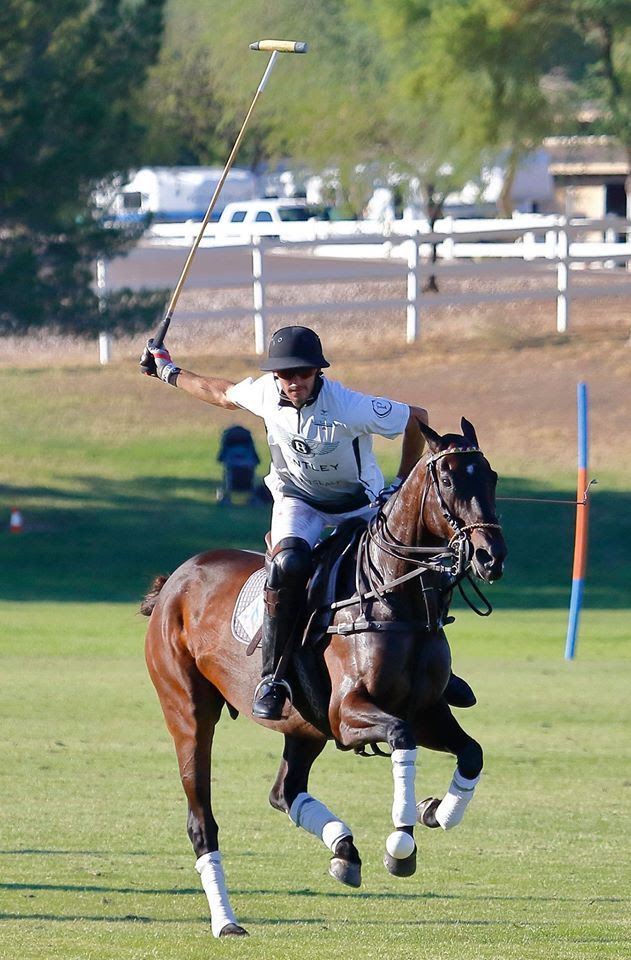 A man is riding a horse while holding a polo stick.