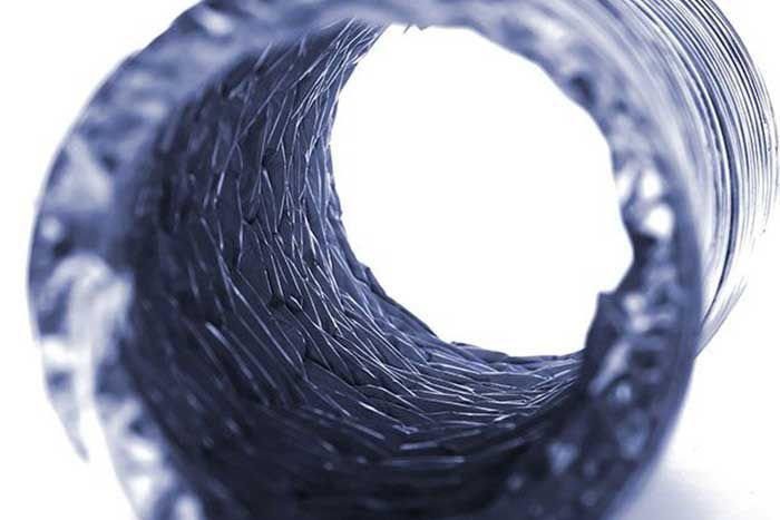 Inside view of a dark blue, textured tube or tunnel opening towards a bright white light.