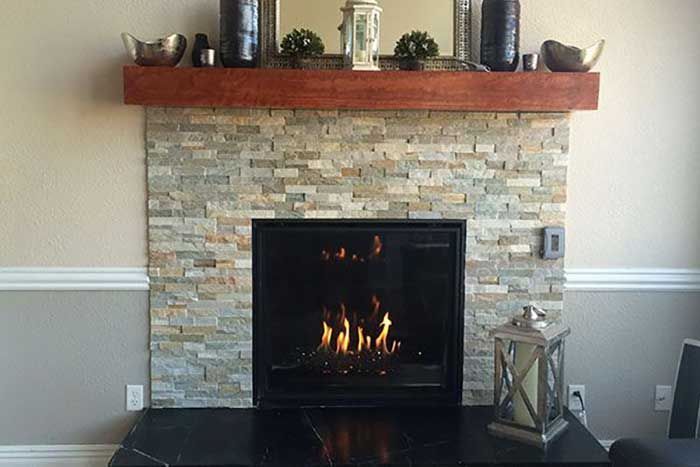 Fireplace with stone surround, dark mantel, and lit fire.