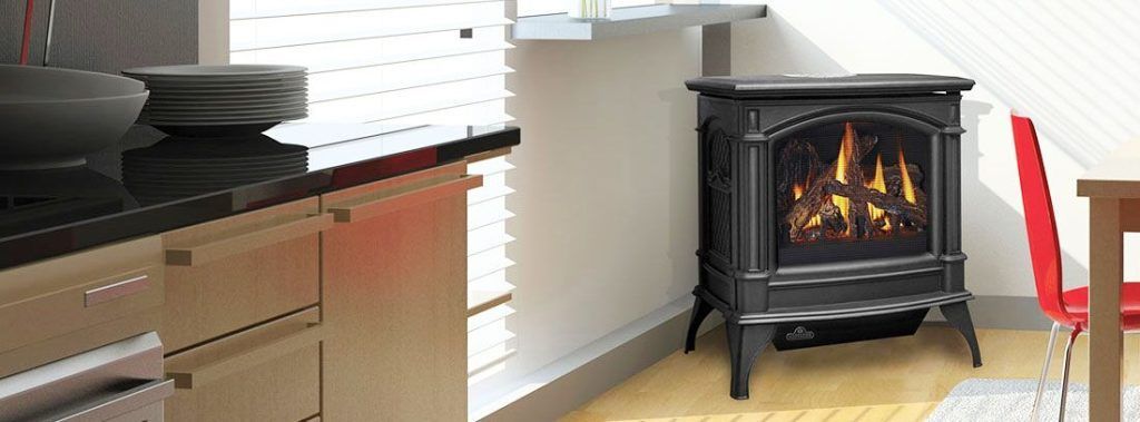 A black fireplace with a burning flame in a room with a red chair and kitchen.