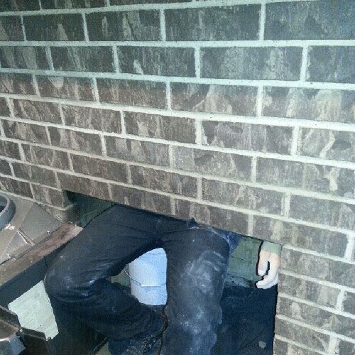 Person working inside a brick wall. Legs and a bucket are visible.