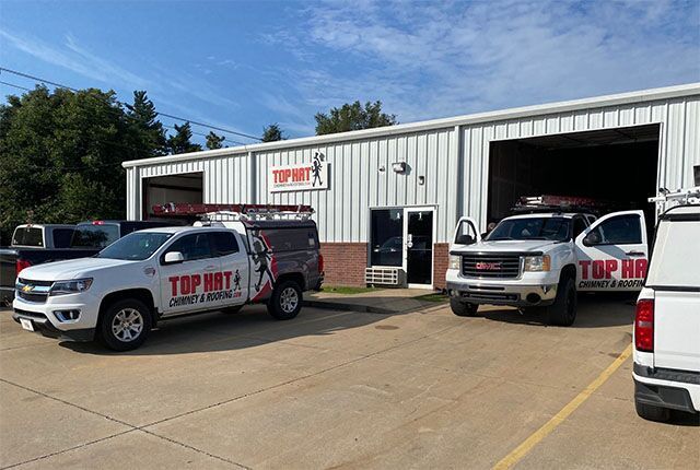 White trucks with company logos parked outside a building with an open garage door.
