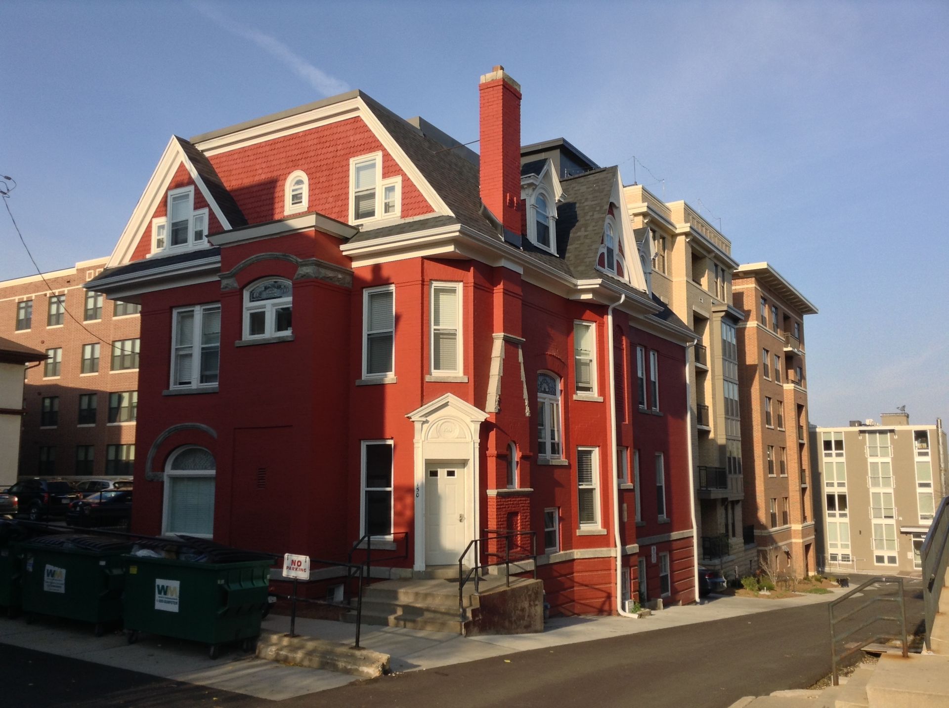 A large red brick building with a green trash can in front of it