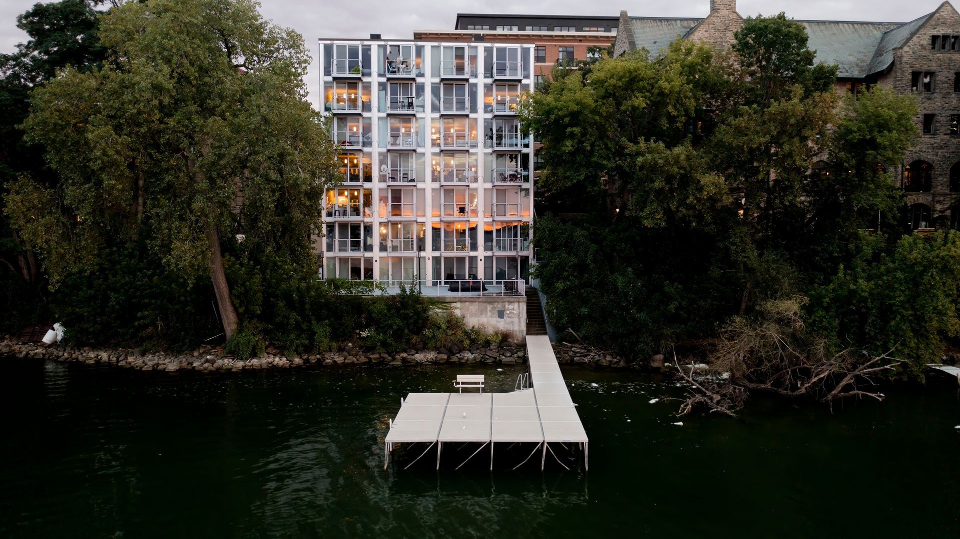 An aerial view of a building next to a body of water with a dock in front of it.